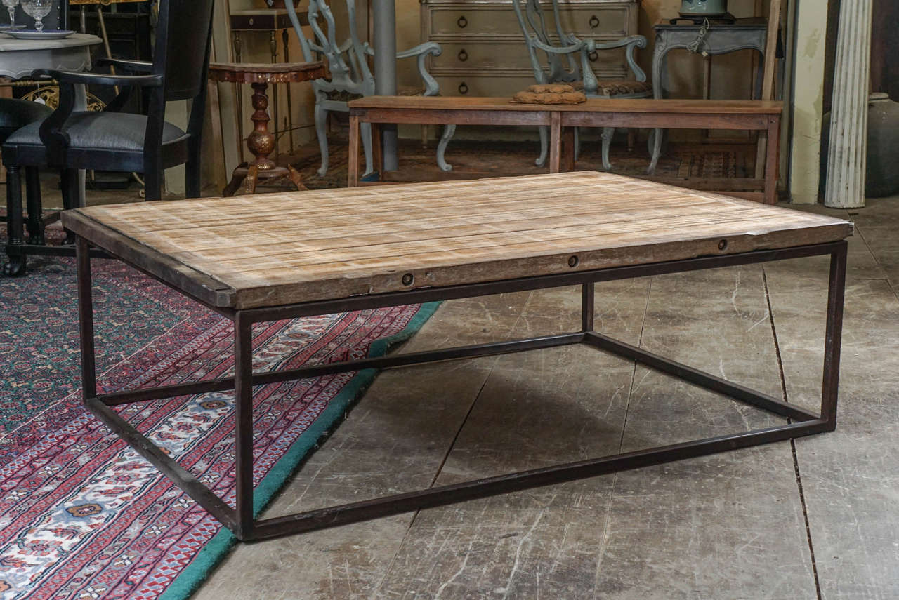 The rustic country style coffee table has an antique French factory wood pellet uniquely constructed with eight wood planks bolted together as a table top. The iron frame wraps around both ends of the top and are bolted as well.
The base is made of