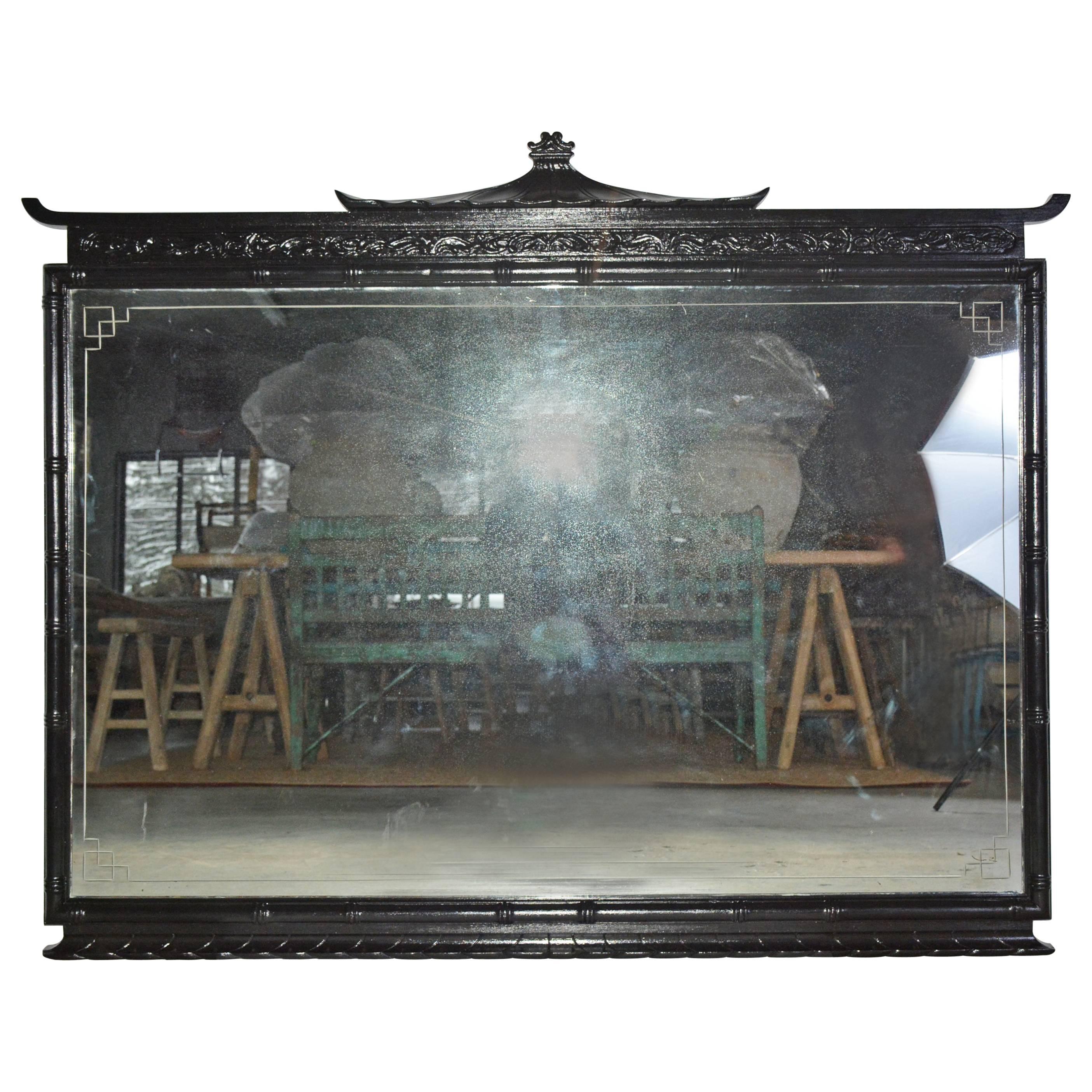 Pagoda chinoiserie style mirror is painted black and has a faux bamboo frame. The mirror has an etched border. Can be used as an over mantel wall mirror or perfect as a dresser mirror.