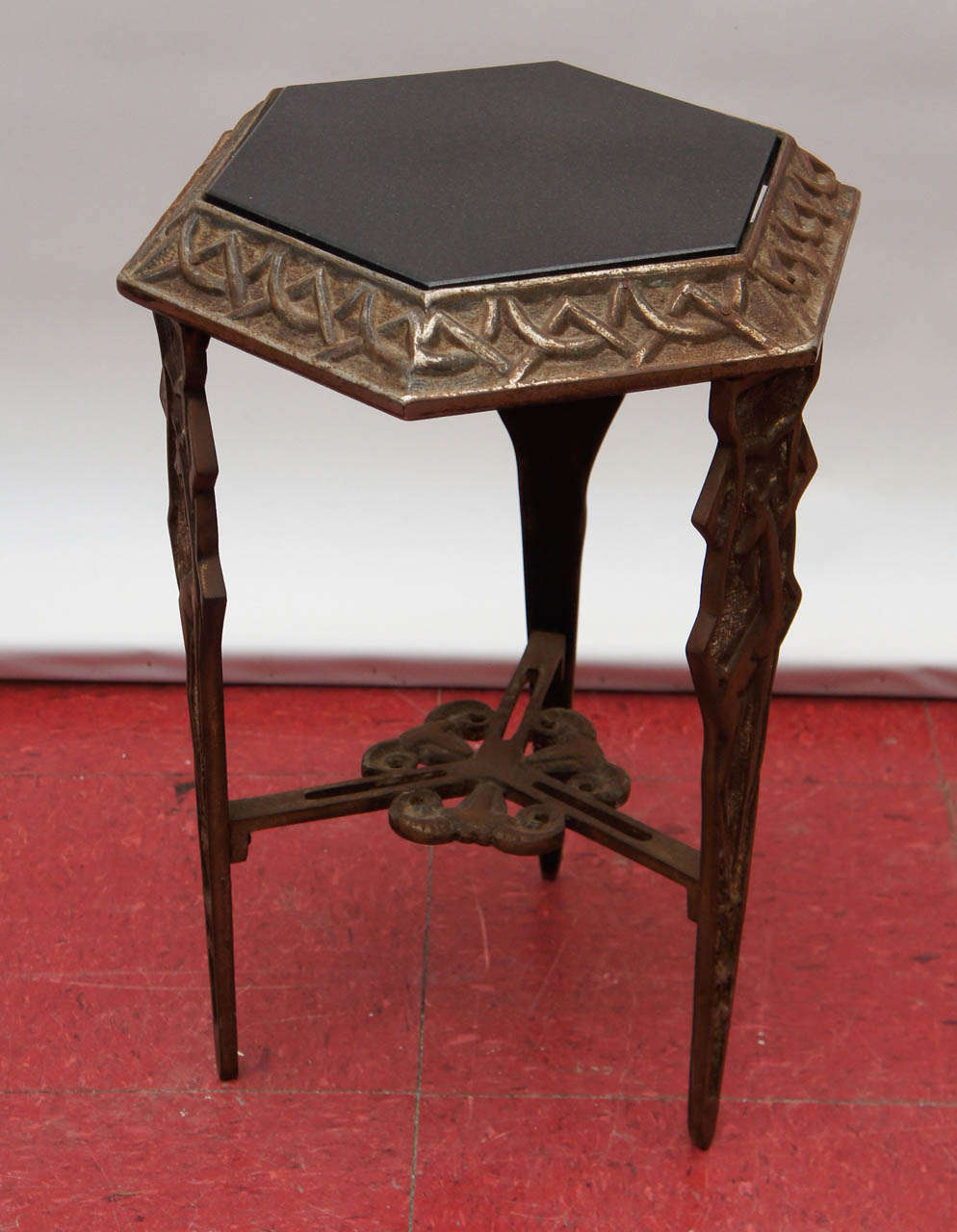 Cast iron figural hexagonal side table with granite inset top, patinated finish, animal figures include a giraffes and rams heads.