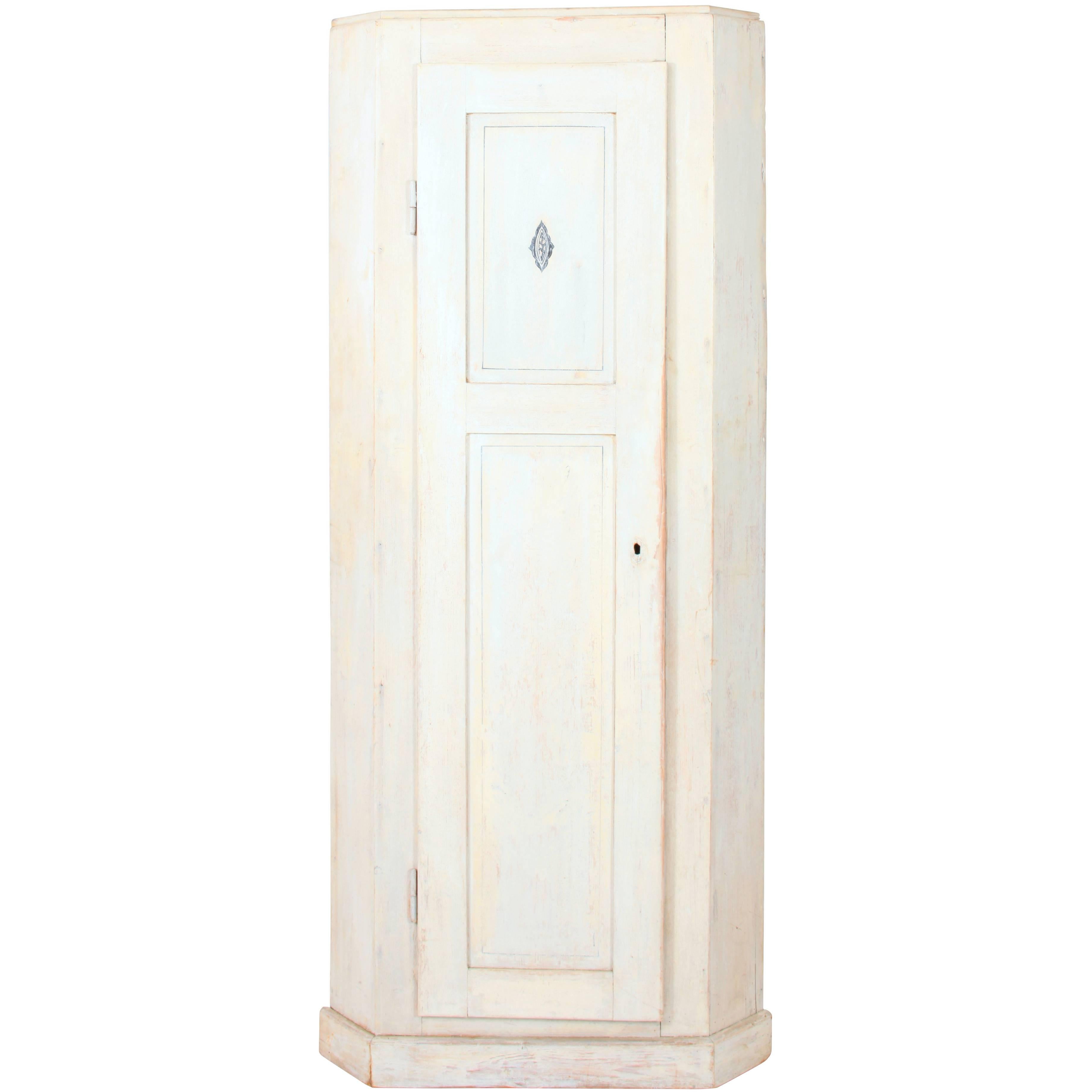 The Swedish corner cupboard, painted pine in grey/white, has a full length paneled door with a blue painted emblem, plank backing, a single shelf at the top inside and molding for holding a second shelf. The inside is unpainted.

Distance from