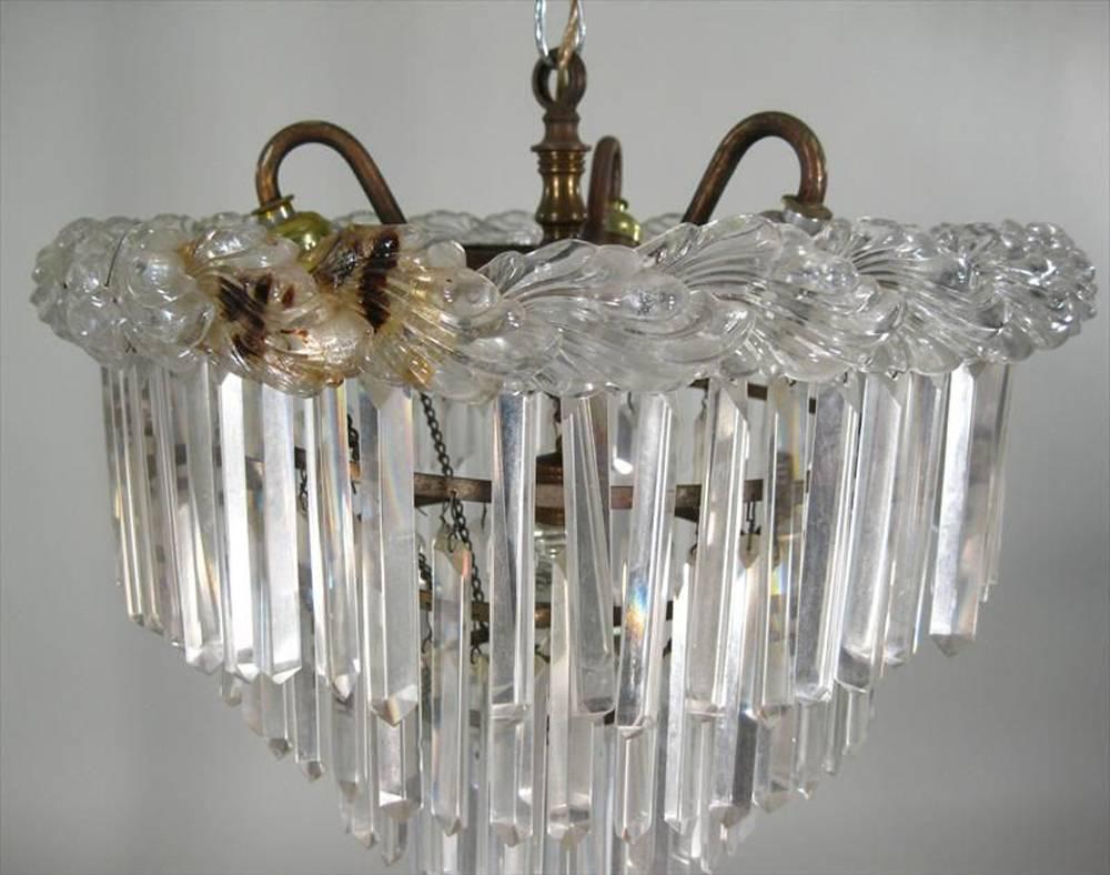 Cut and press glass four-tiered hanging light fixture, top with leaf-form pressed glass border, having four circular tiers with hanging cut-glass prisms, electrified with three arms.