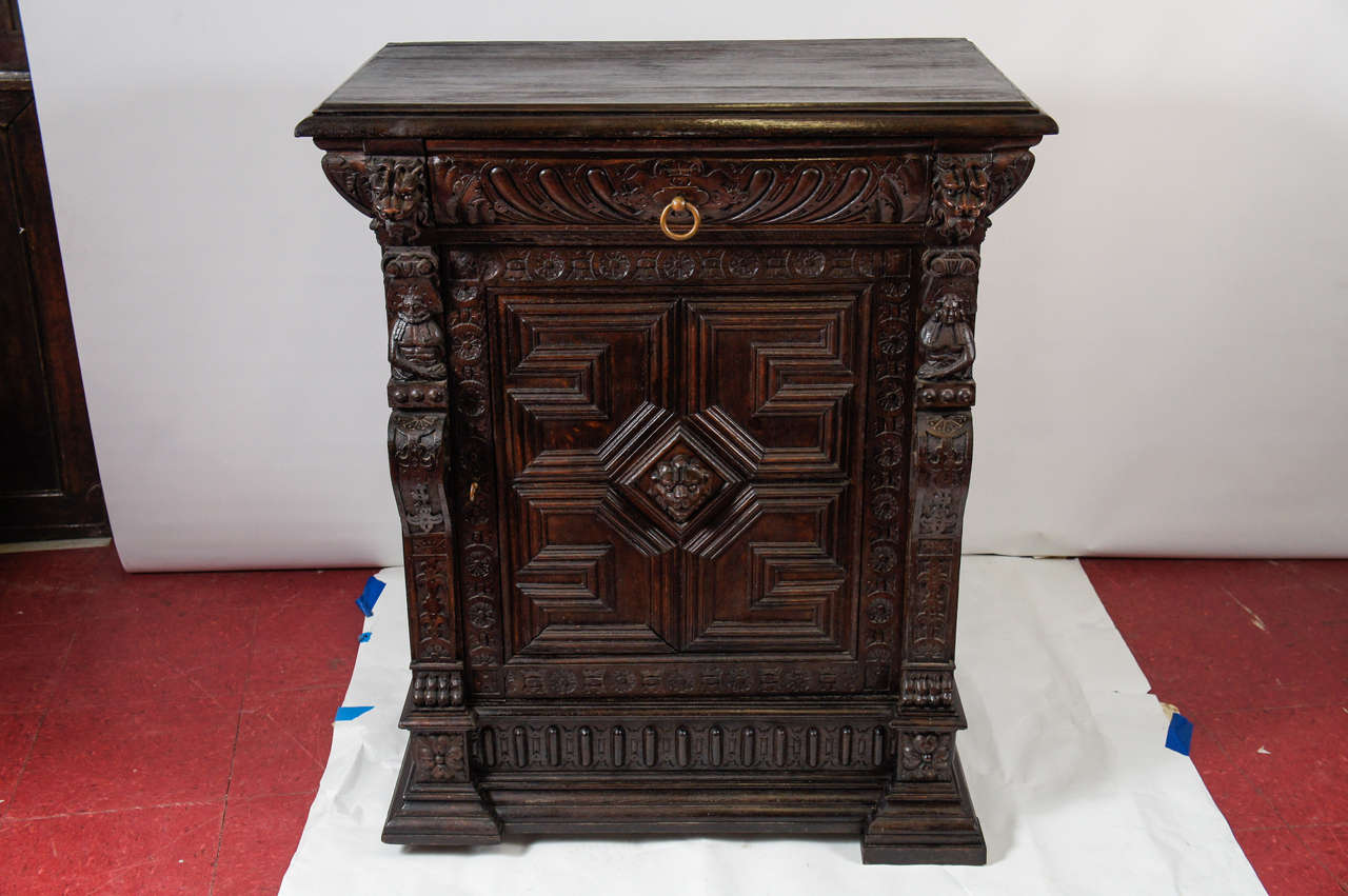 Renaissance-style or baroque oak cabinet has an elaborately carved front that includes a single dove-tailed drawer and two-shelf cupboard, the door of which had a centred lion's head. A pair of carved pilasters have lion's heads at the top with open