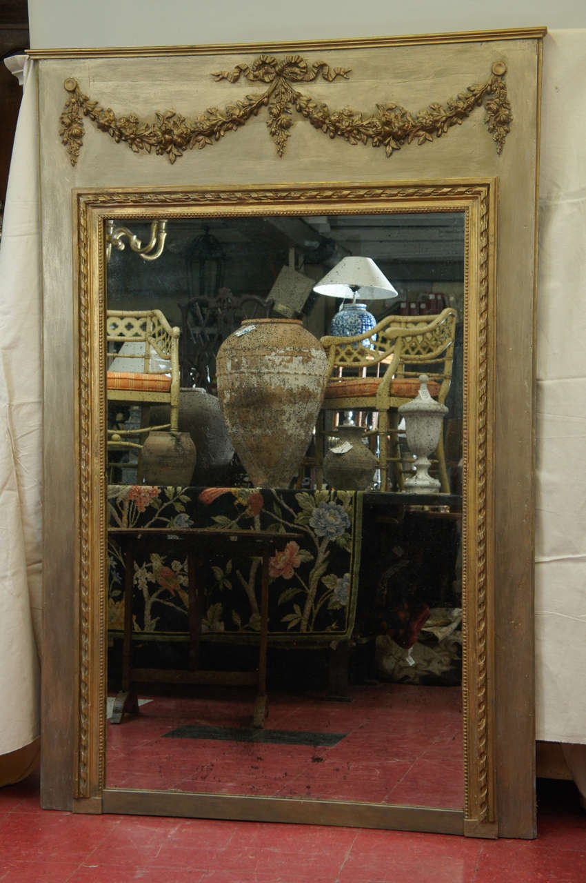 Originally part of a boiserie room panelling with swags and rope design molding framing the mirror. Mirror is distressed. Can be replaced with new flat or bevelled mirror.