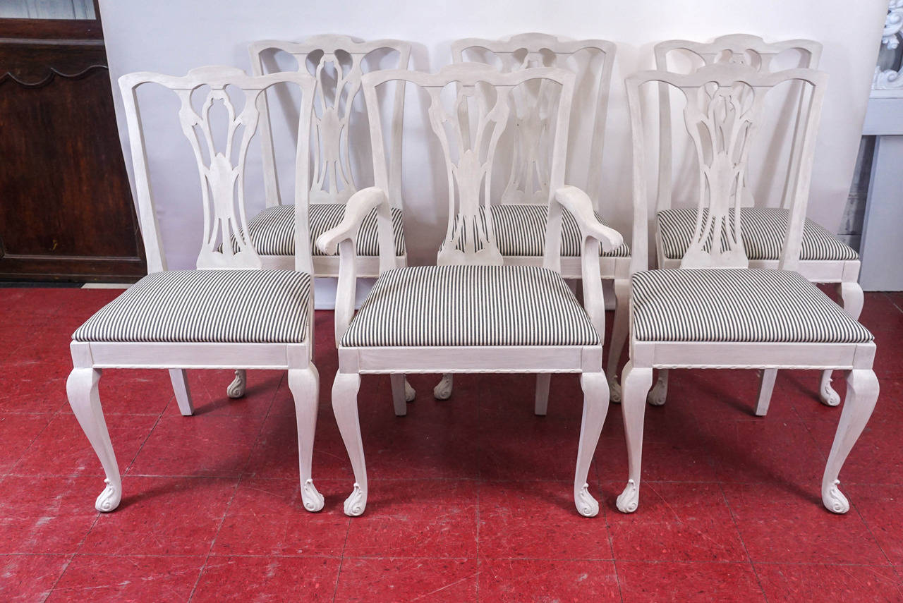 The six elegantly carved chairs are composed of five side and one arm, all newly painted in cream. The frames are secured by angled blocks at all corners. The padded pop-out seats are upholstered in new cream and black stripe cotton