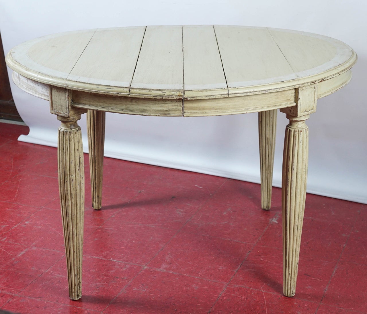 Gustation style painted cream with a greenish tint and a white boarder, the table has tapered fluted legs and is extendable. Leaves are not available. Excellent as a kitchen table.