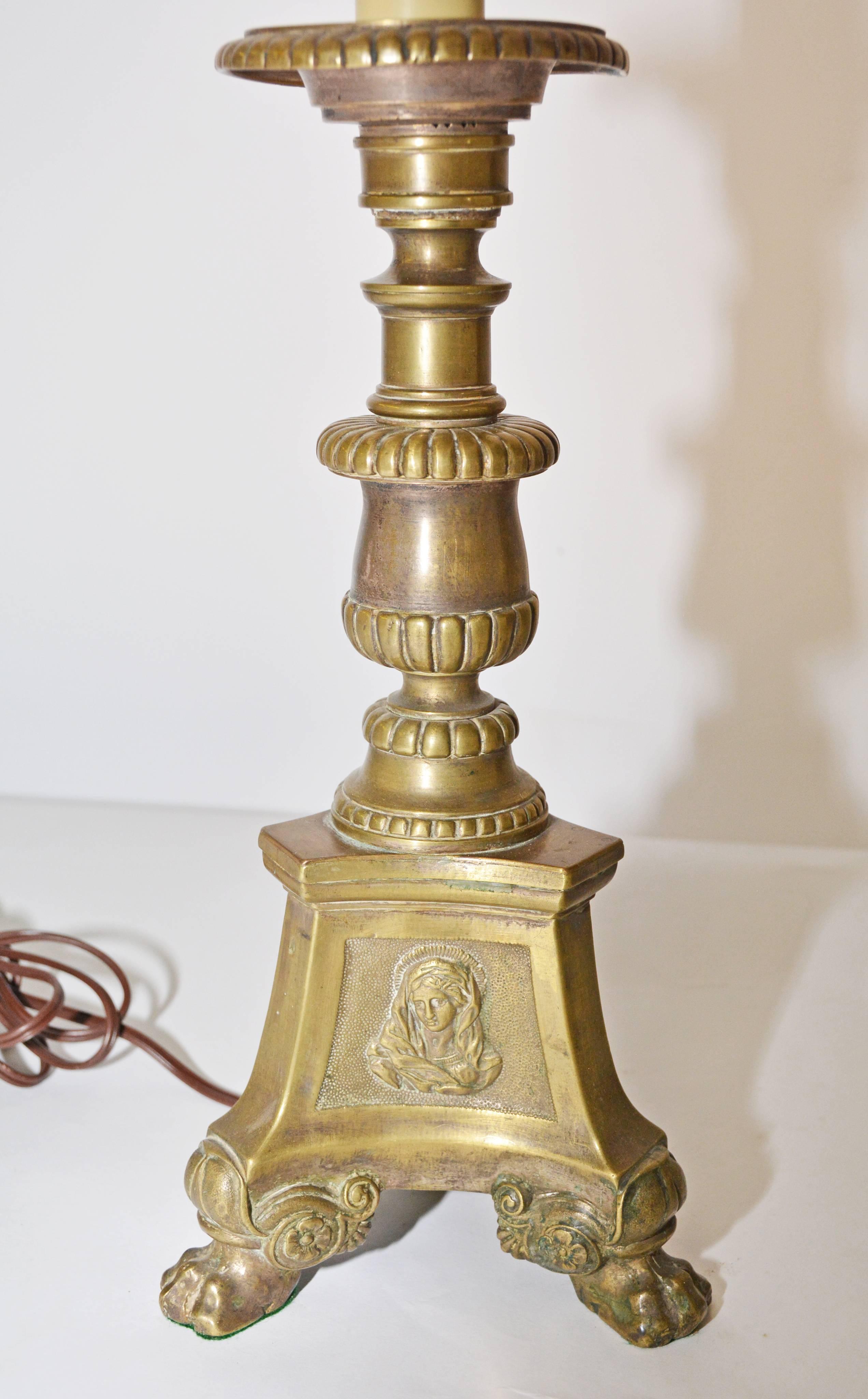 The lamp base is made from three-sided bronze altar candlestick embellished with religious symbols en relief, as well as classical detailing and claw feet. The shade is for photo purposes only.  It has some staining.  Can be included if needed--no