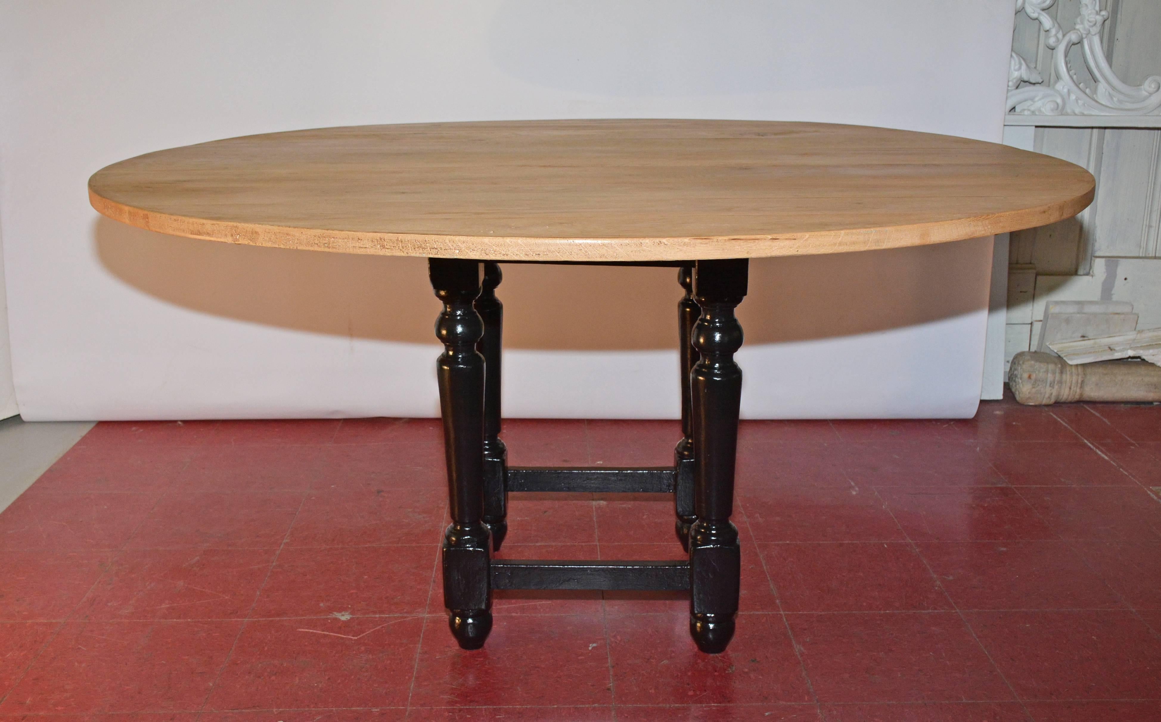 The round teak wood top of this dining table has been married to an antique pedestal cage base painted black and will seat up to eight people. The base has stretchers for securing the round legs and measures: 18.50