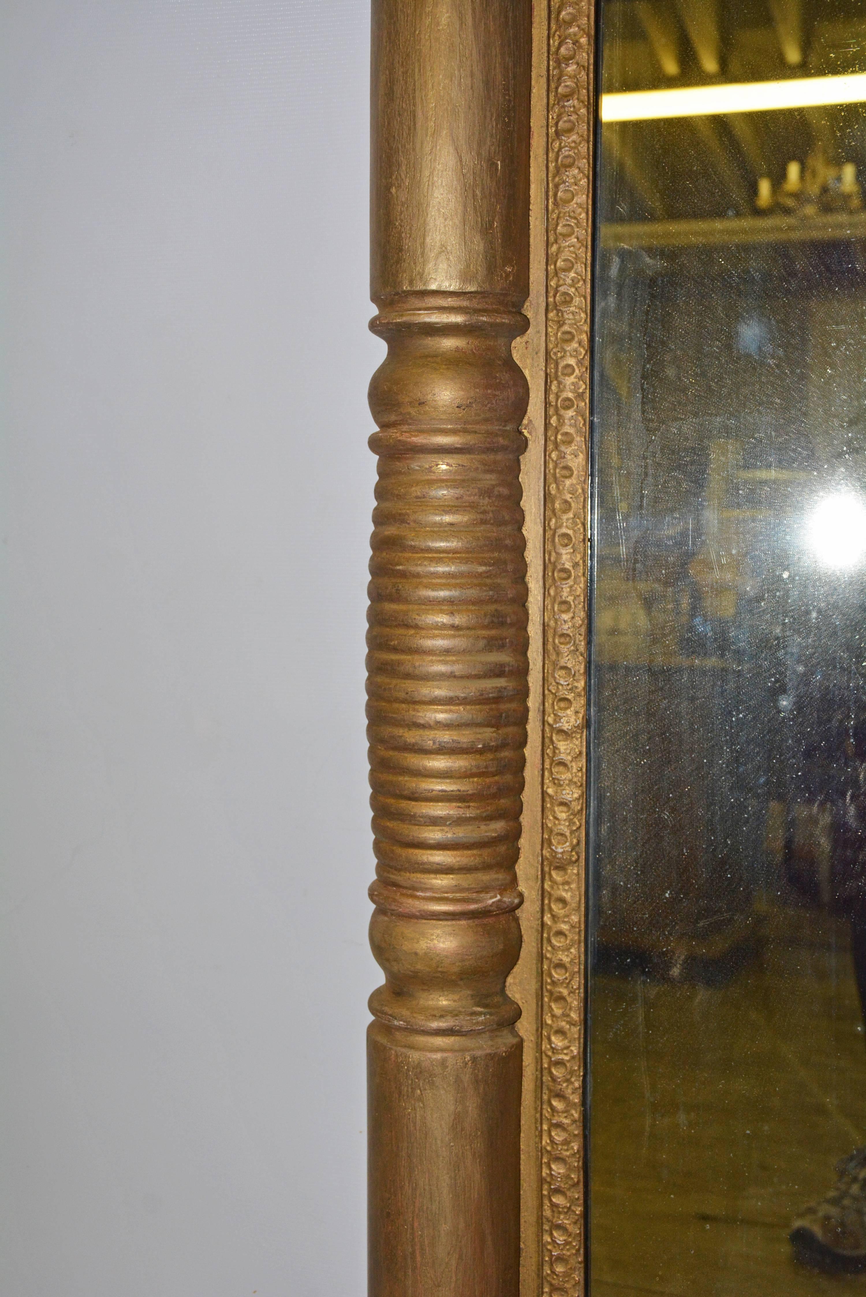 Le miroir argenté de style fédéral de la fin du XIXe siècle est composé d'une alternance de pilastres à sections nervurées et lisses se terminant aux angles par des blocs carrés. Le support est composé de six planches horizontales et est câblé pour