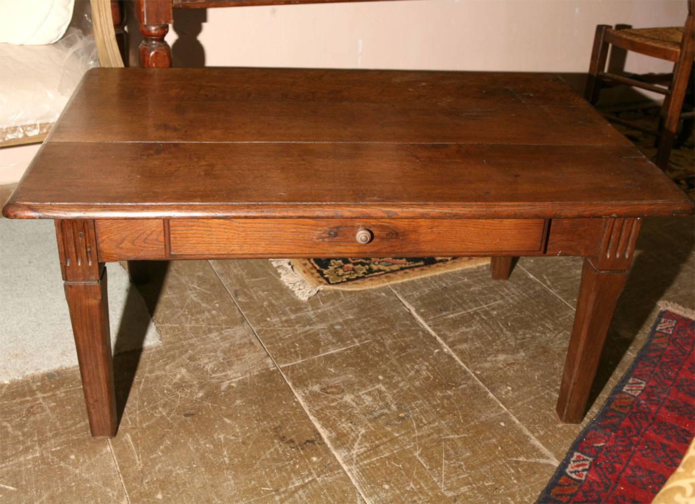 Rustic French country style rectangular cocktail table with plank top, four tapered legs and one facing drawer. Great aged patina and character.