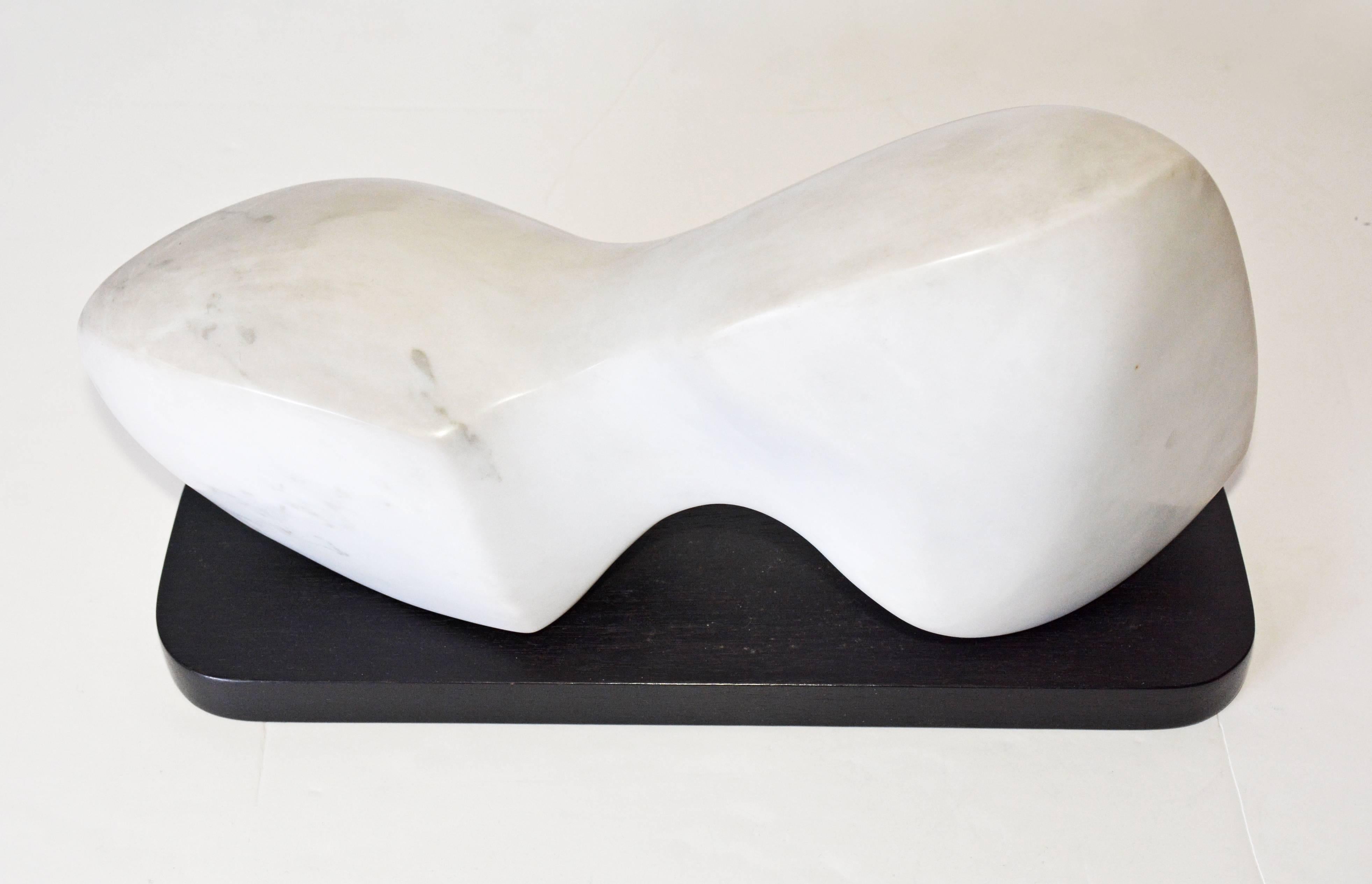 The contemporary white veined marble sculpture sits on a black wood base. Sculptor is Jean Downey, (1931-2009). She was born in Canada, studied art in Illinois, New York and Connecticut. Her work is included in private and corporate collections in