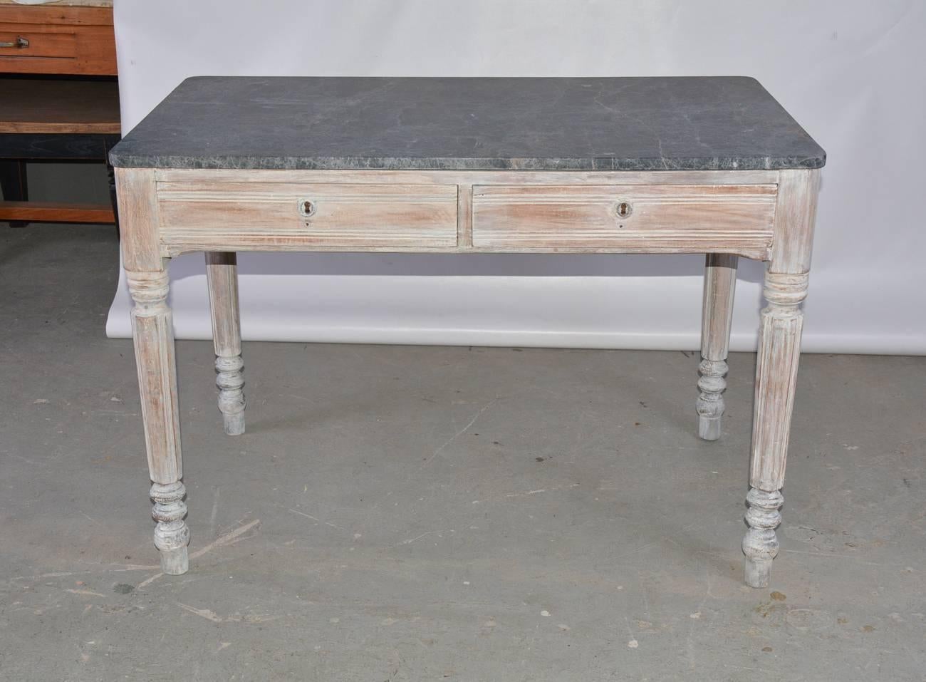 The antique country marble-top desk has two deep drawers, fluted and turned legs and the look of a white-washed finish. The drawers have key holes but no key.

  