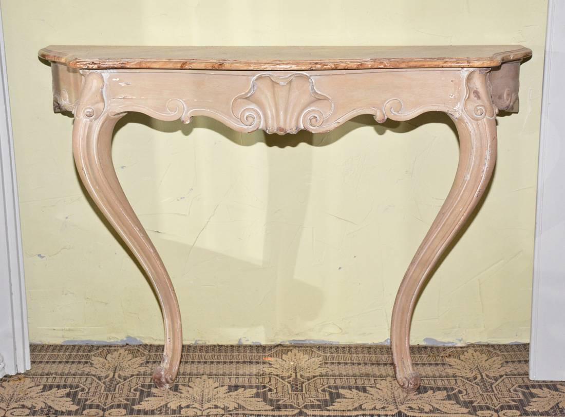 Cette console ou table d'entrée ancienne en bois sculpté à la main est de style rococo vénitien. La couleur des pieds et du cadre est brun clair et le dessus est peint en faux marbre dans des tons de brun et de jaune ocre. Des trous dans le tablier