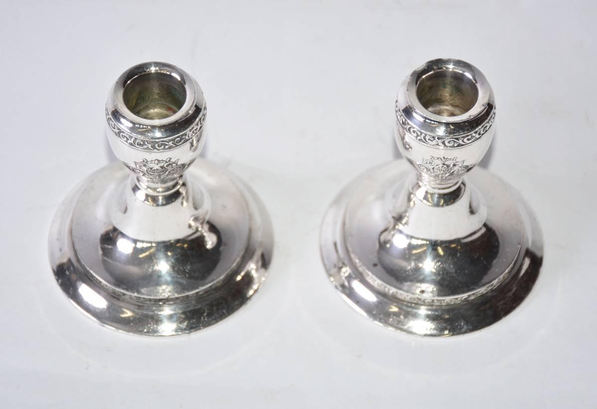 The pair of vintage candleholders are made of silver plated metal and have embossed stylized shields. The candleholders are stamped 
