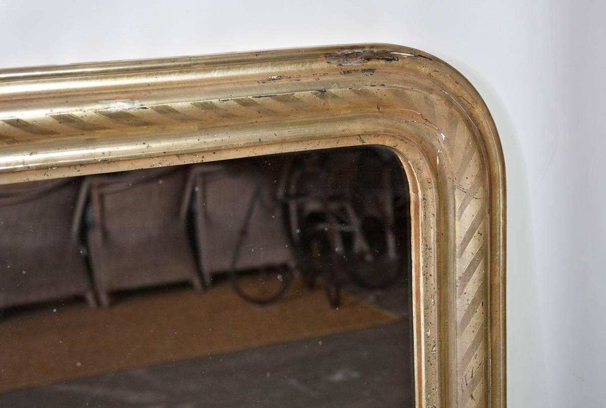 19th century French Louis Philippe mirror has a wide frame painted with silver gilt with a spiral pattern and has wood panels across the back. Ready to hang.