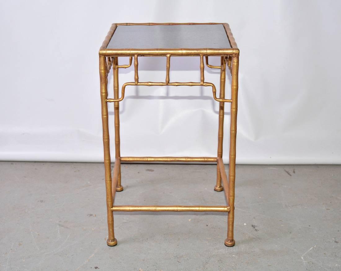 The vintage faux-bamboo occasional table in the Chinese style is composed of gilt metal and an inset black polished marble top. Great as a side or plant table.