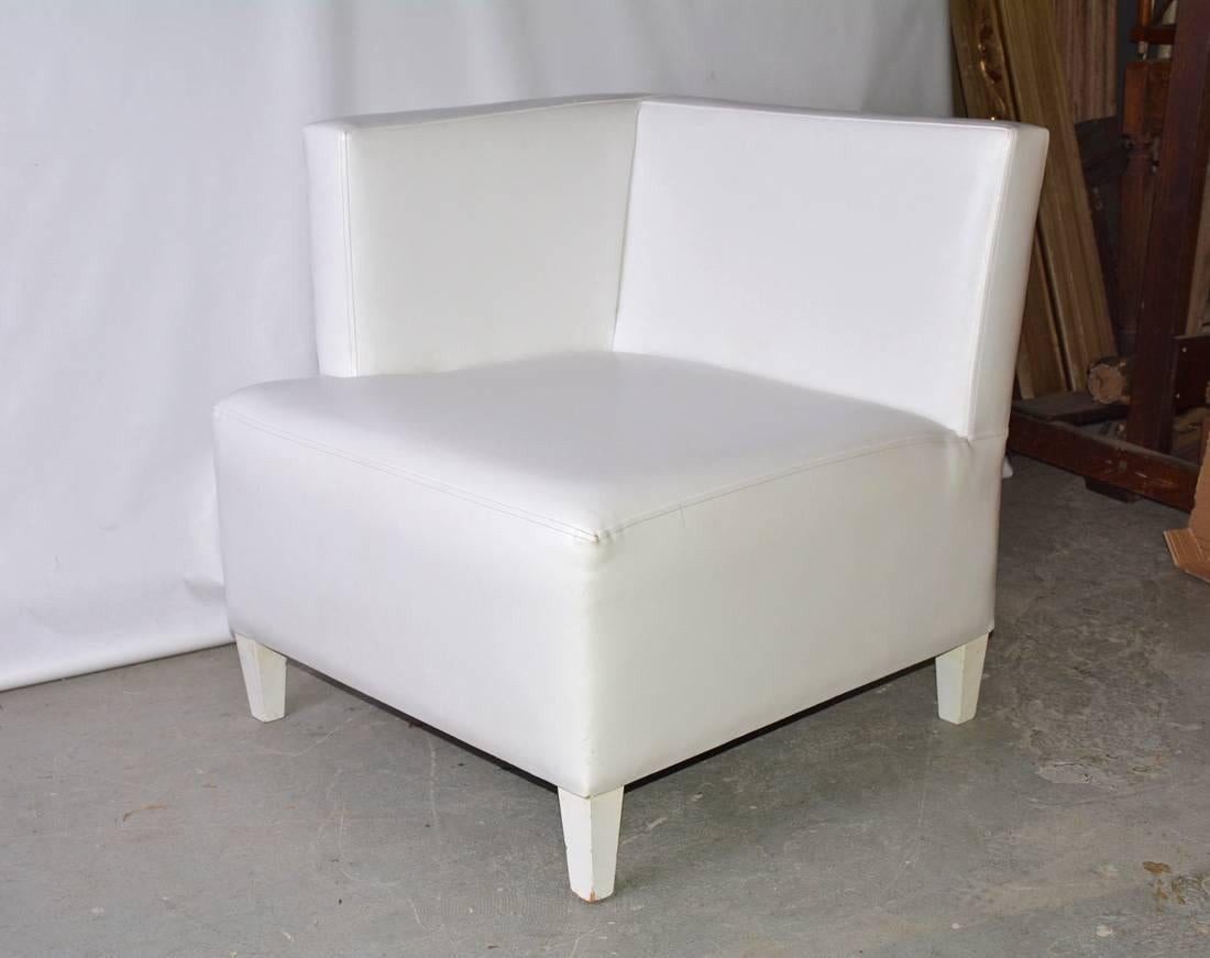 The contemporary single arm corner club chair is upholstered in white leather and the tapered wood legs are painted white.
