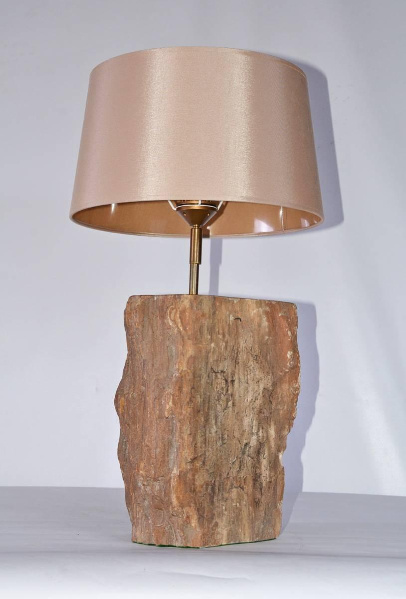 La base de la lampe de style contemporain est en bois pétrifié brun du 15e siècle ou plus ancien et est électrifiée pour une utilisation aux États-Unis. L'interrupteur est fixé au cordon électrique. L'abat-jour est un tissu soyeux avec une doublure