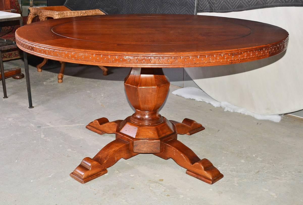 The vintage dining, library or conference table has a center urn-shaped pedestal with four splayed feet. The top has a framed border with the wood cut in pie shapes and a incised ring. The apron is a series of hand-carved 