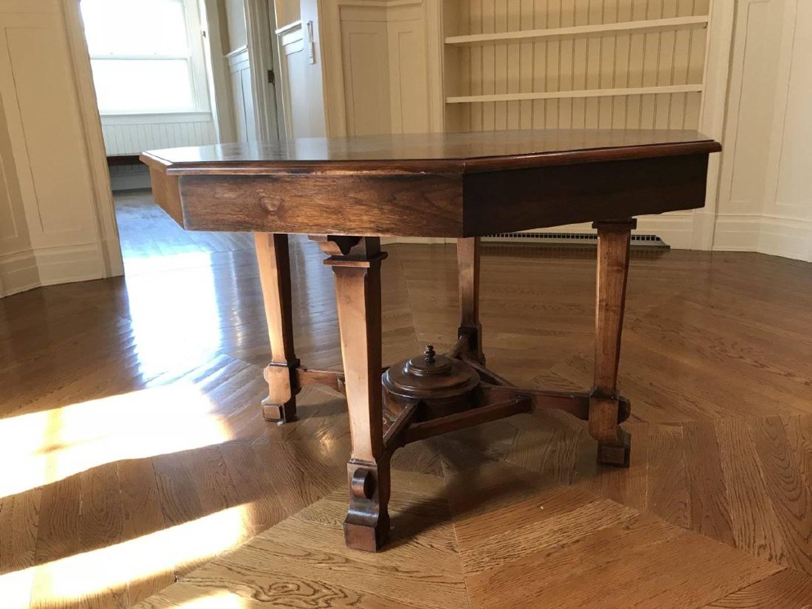 English Regency Revival antique circa 1900 octagonal mahogany center, parlor or library (for reading or displaying books and magazines) table refinished in a mahogany tone. The table features a six-sided top with an apron, supported by four legs and