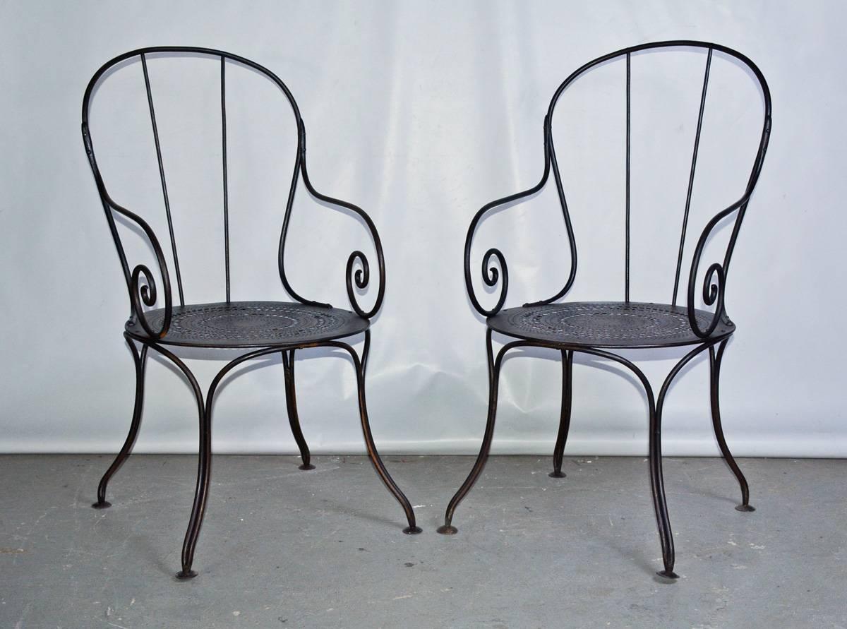 The pair of antique French outdoor public park or garden metal armchairs, made of wrought iron painted black with pierced pattern iron seats. Bistro style chairs. Think of them as stylish occasional chairs for the porch or patio.
 