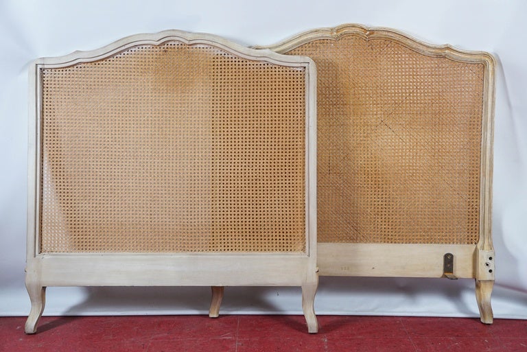Pair of Louis XV style twin size headboards with carved white-with-yellow-glaze frames and natural cane panels.