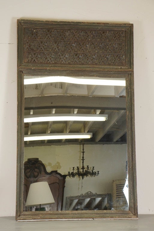 This unusual early mirror has hand-carved decorative details at the top with rosettes imbedded in a hexagonal sectioned panel. The deep frame is covered in years-old green paint, while the panel is not painted. The mirror is new.