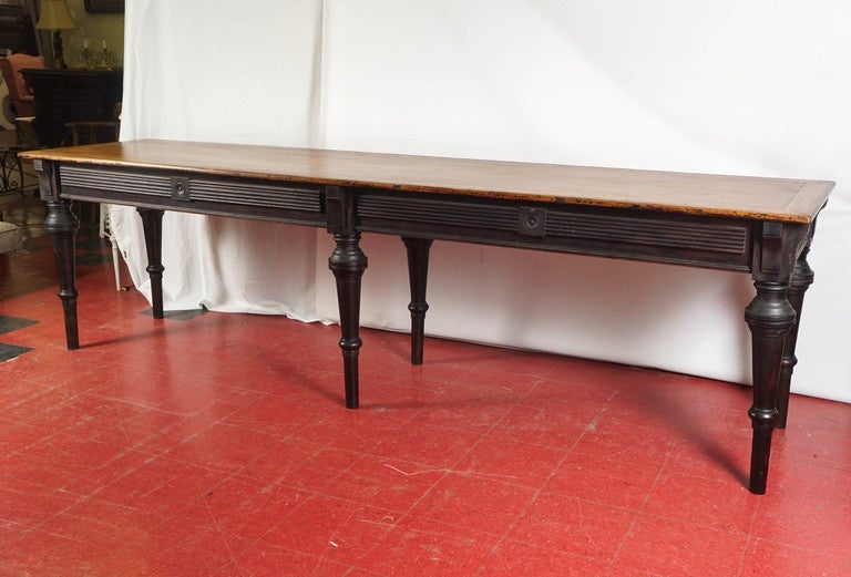This extra-long draper's work table has a stained black base and a waxed and framed top. Because of its height, it works especially well as a server, kitchen center Island, library table or in a hotel lobby.