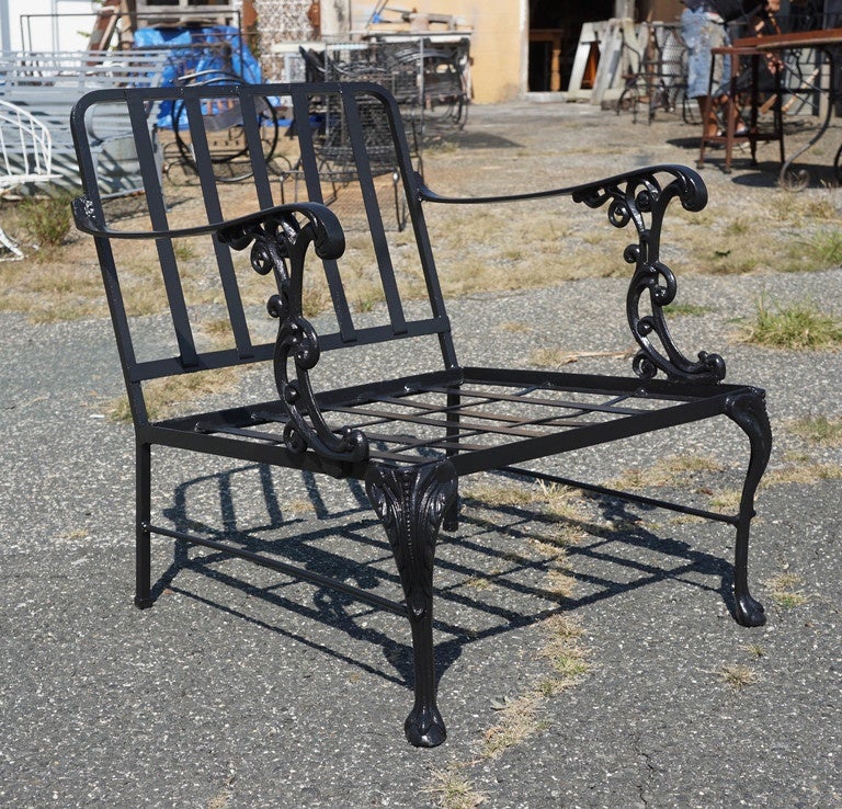 This set of 3 outdoor metal garden seating ensemble has generously wide, wrought-iron chairs, arms decorated with rococo supports, as well as cabriole legs.  The matching two-tier table has similar features.  Third matching chair with ottoman is