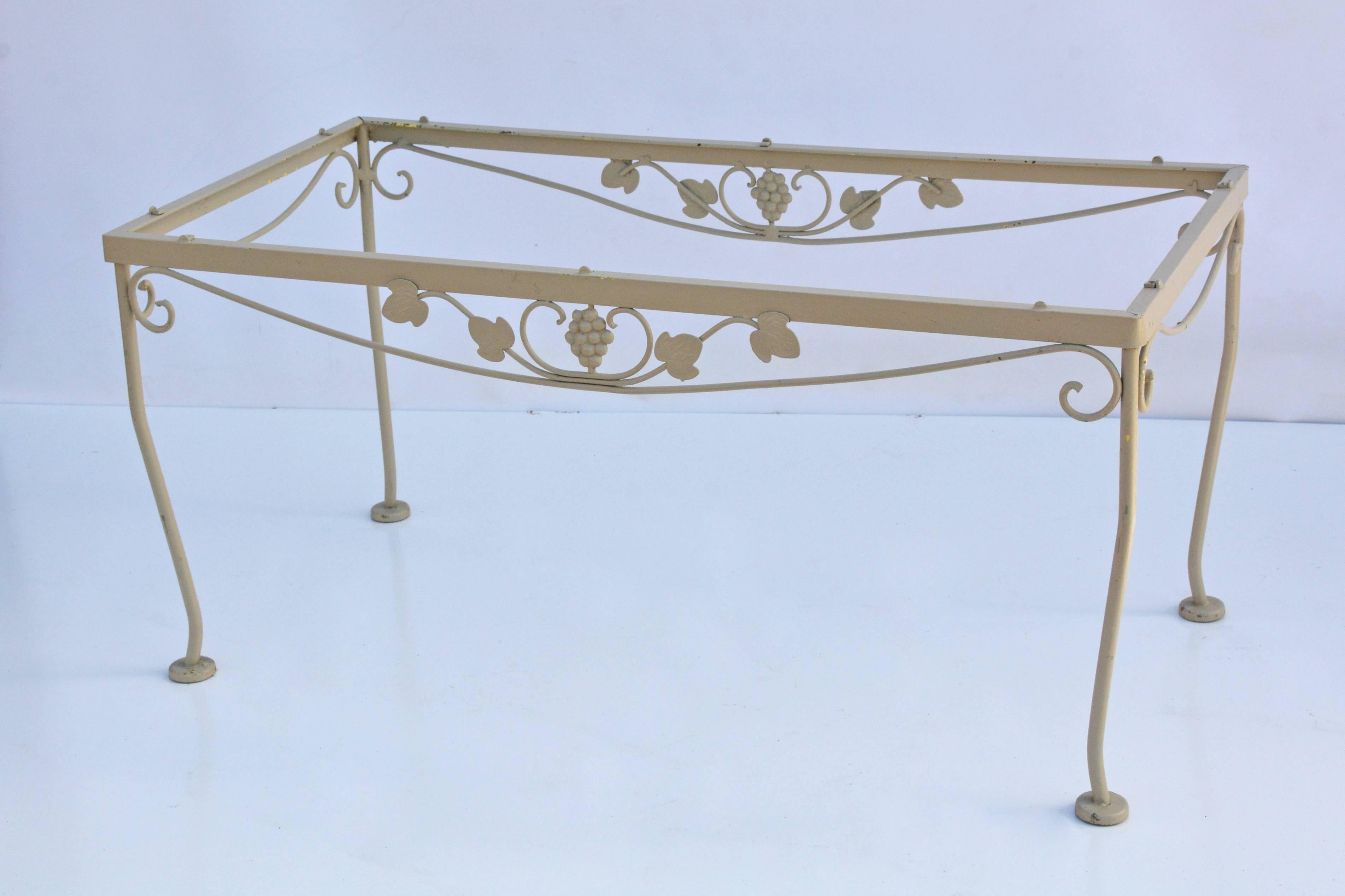 The table is wrought iron painted cream and embellished with grapes and leaves. Tabs are in place for holding a required glass top. The feet are hollow for holding pads to prevent floor scratches. See other matching pieces.