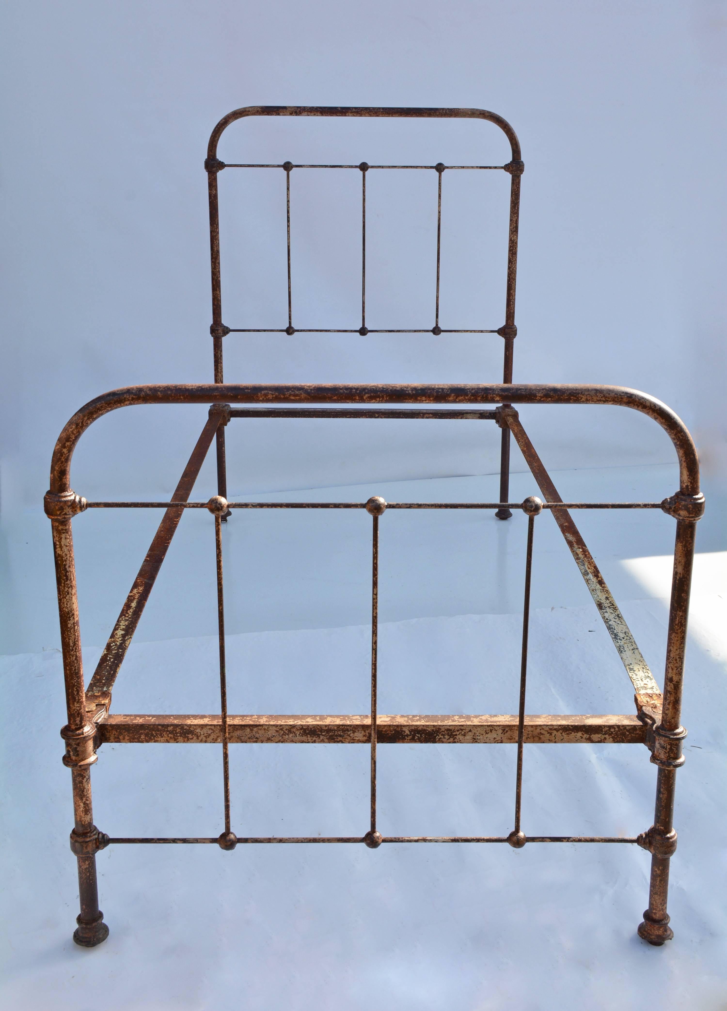 The antique country iron twin size bed has L-shaped side railings with protrusions that slide into slots attached to the head and foot boards. The railings will hold the mattresses. 

Footboard: 34.50