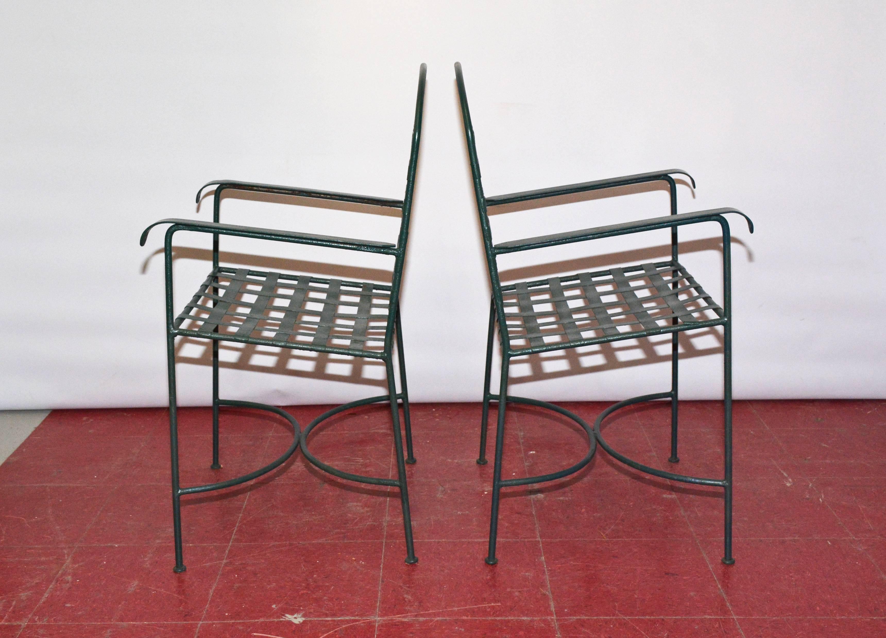 Painted dark green, the wrought iron outdoor chairs are made with woven slated seats and backs and flat arm rests, The legs are secured with semi-cirular stretchers. No number.

Measures: Arm 25.25