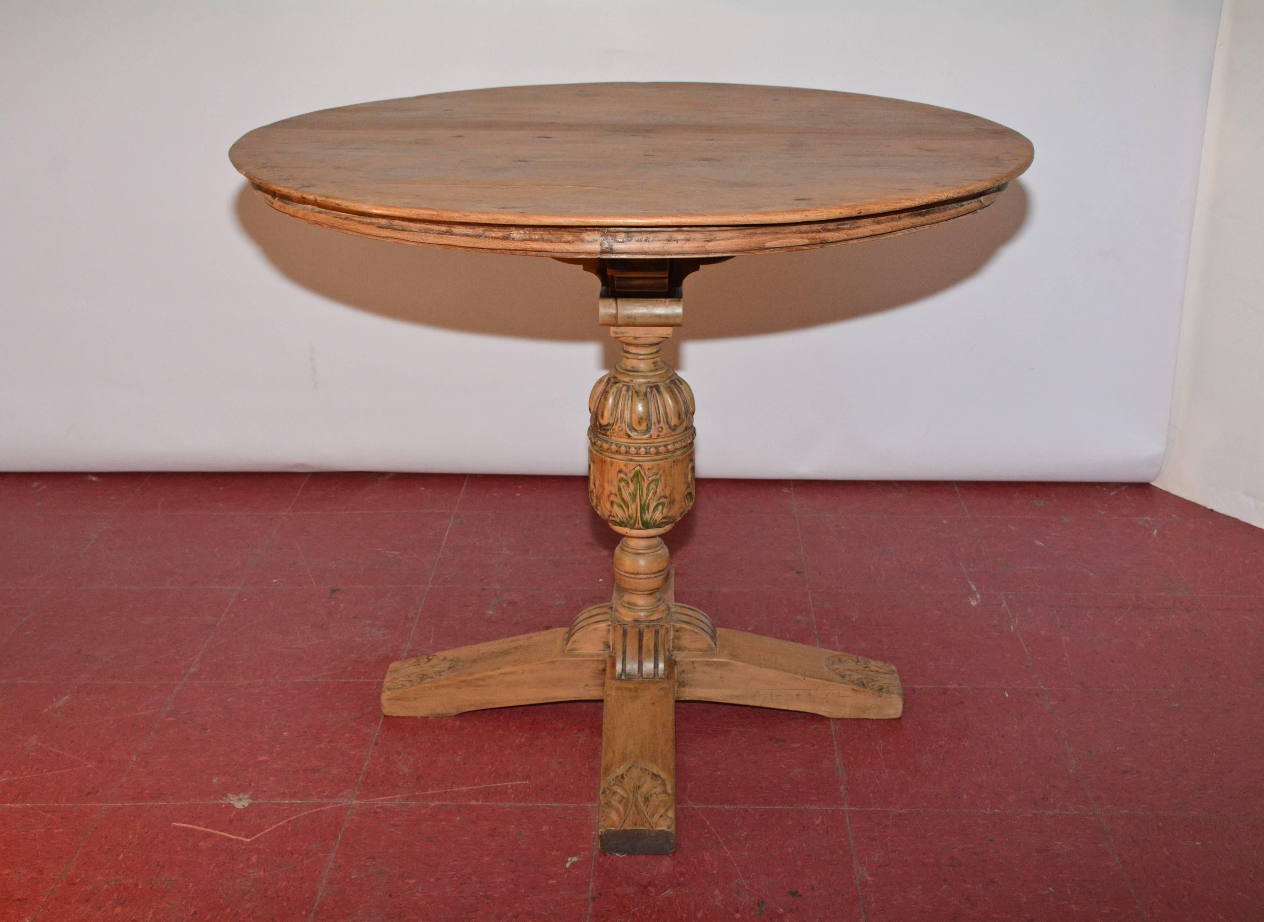 The round table is composed of rusticated fruitwood top with crisscross framing underneath attached to Jacobean-Revival pedestal base. The oak base is decorated with carved acanthus leaves, beading and an Ionic capital. Waxed finish.