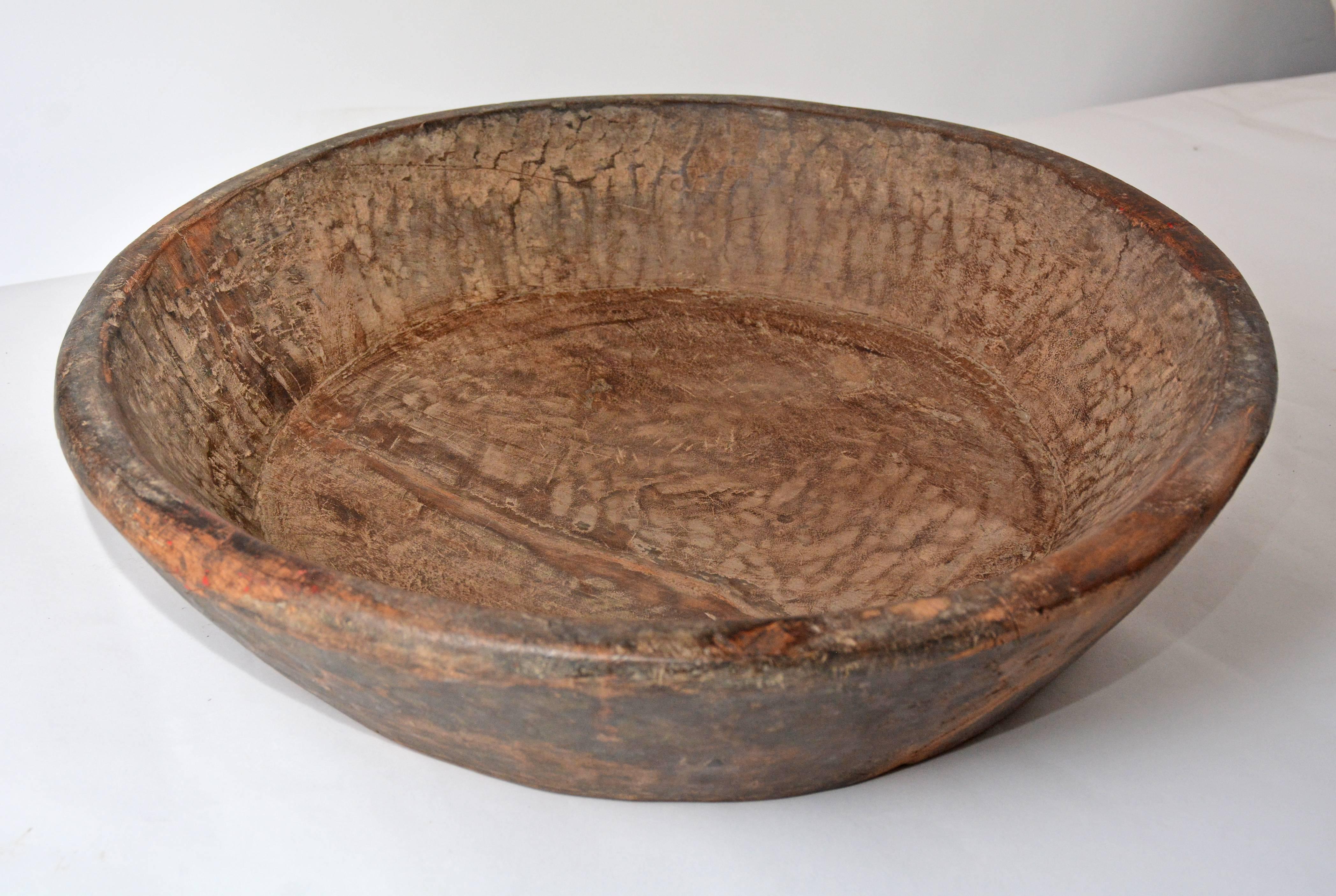 Made of a dense, heavy wood, the antique hand-carved bowl has a flat bottom and tapered sides. Chisel marks are readily seen.