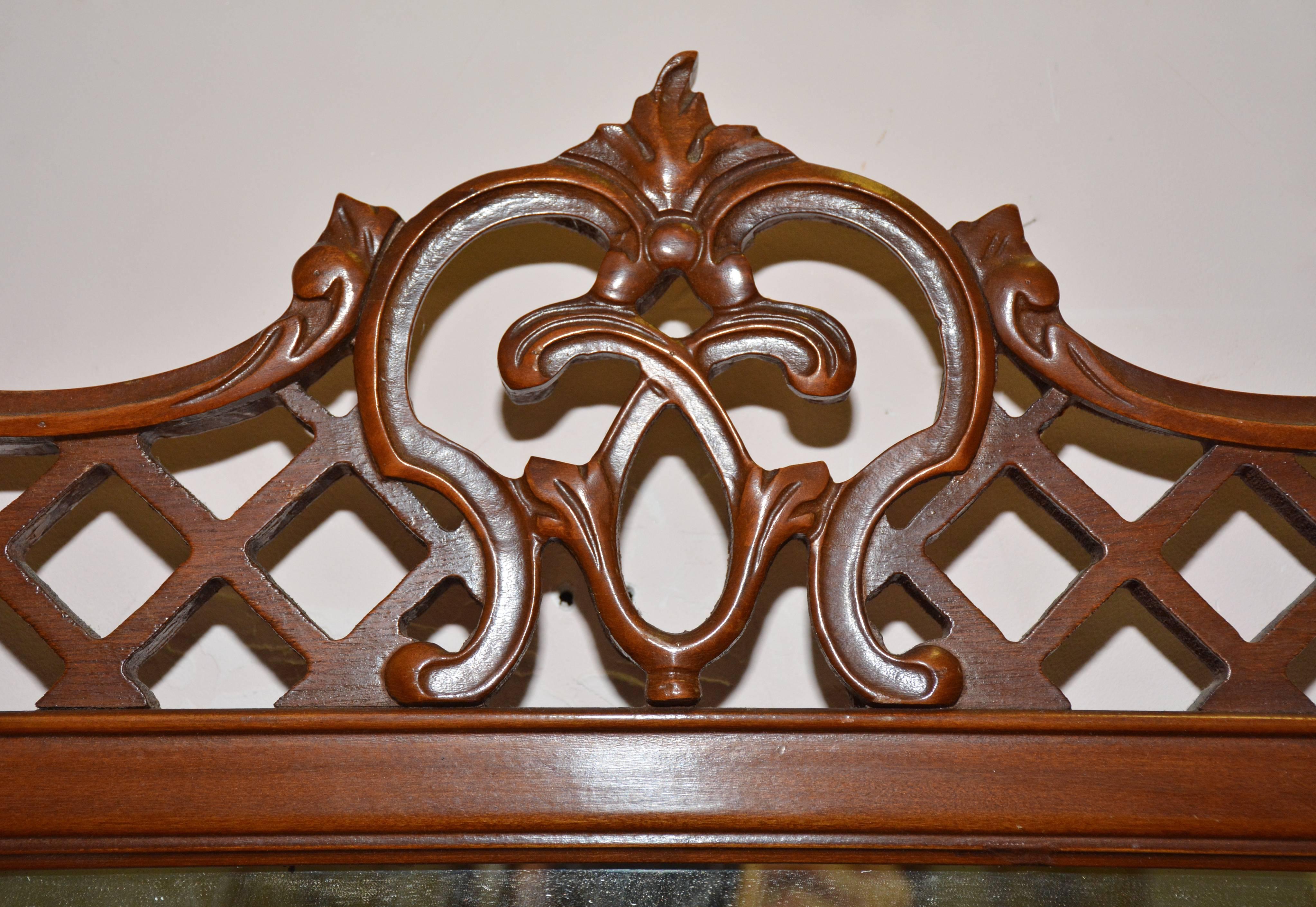 Pair of vintage neoclassical Chippendale style mirrors decorated with fretwork pediments and finials, faux bamboo sides and centered fretwork and ball finials at the bottom. The backs are covered in plywood and are wired for hanging.