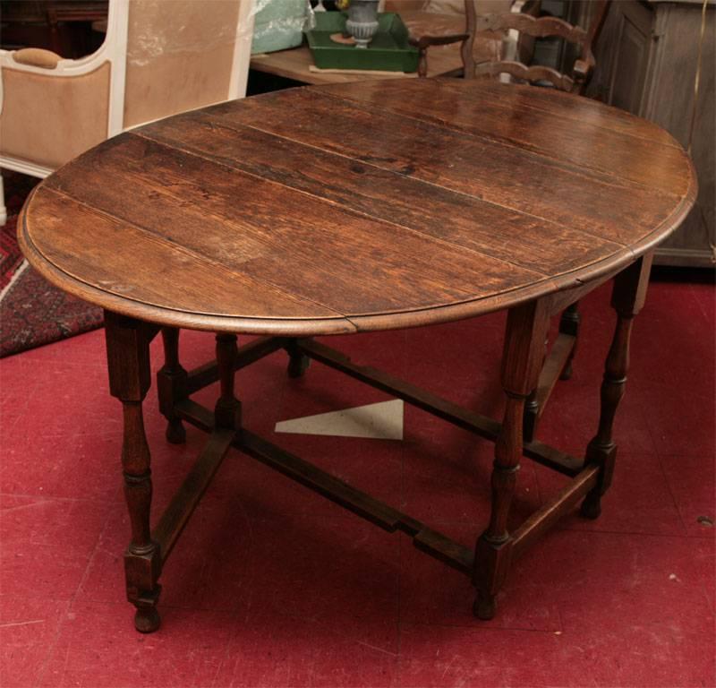 Patina only true age can deliver. Wonderful drop leaf or gate leg kitchen or dining room table with graceful turned legs. Can also be used as a sofa table, console table or entry way table.  Tables shows stain and ware from many years of use but