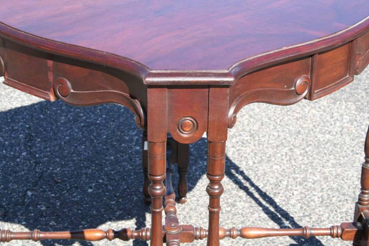 Elegant game table with graceful spindle legs and stretcher. Top made with book matched flamed mahogany veneer. There are a few small missing molding pieces but not very noticeable.