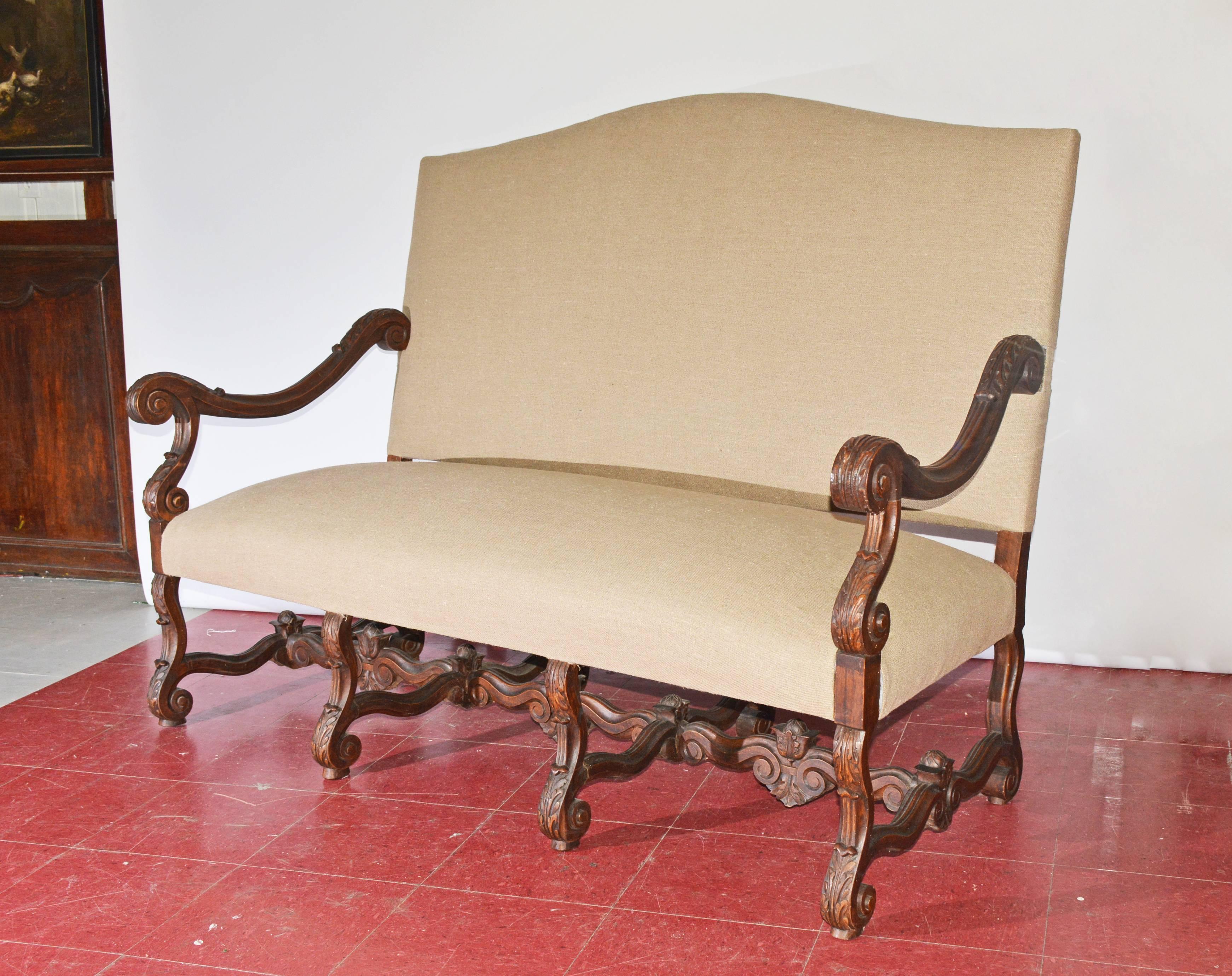 The Louis XV or Baroque Thorne style sofa or settee has hand-carved oak arms, legs and stretchers decorated with leaves and curling volutes. The newly applied upholstery is light brown linen. The seat is cushioned with padding and steel