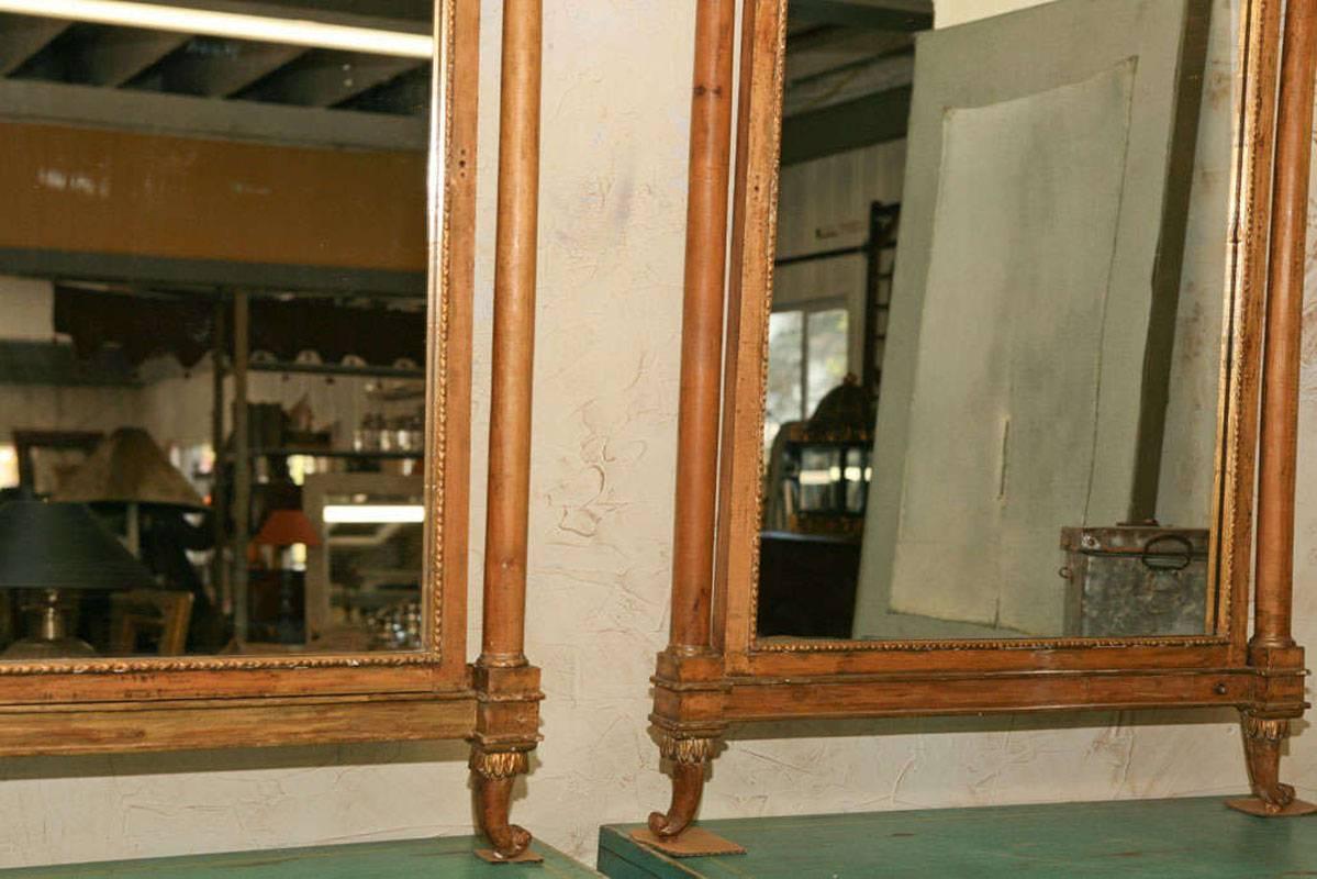 Unusual pair of Empire style giltwood mirrors with large griffins, scrollwork and columned sides.