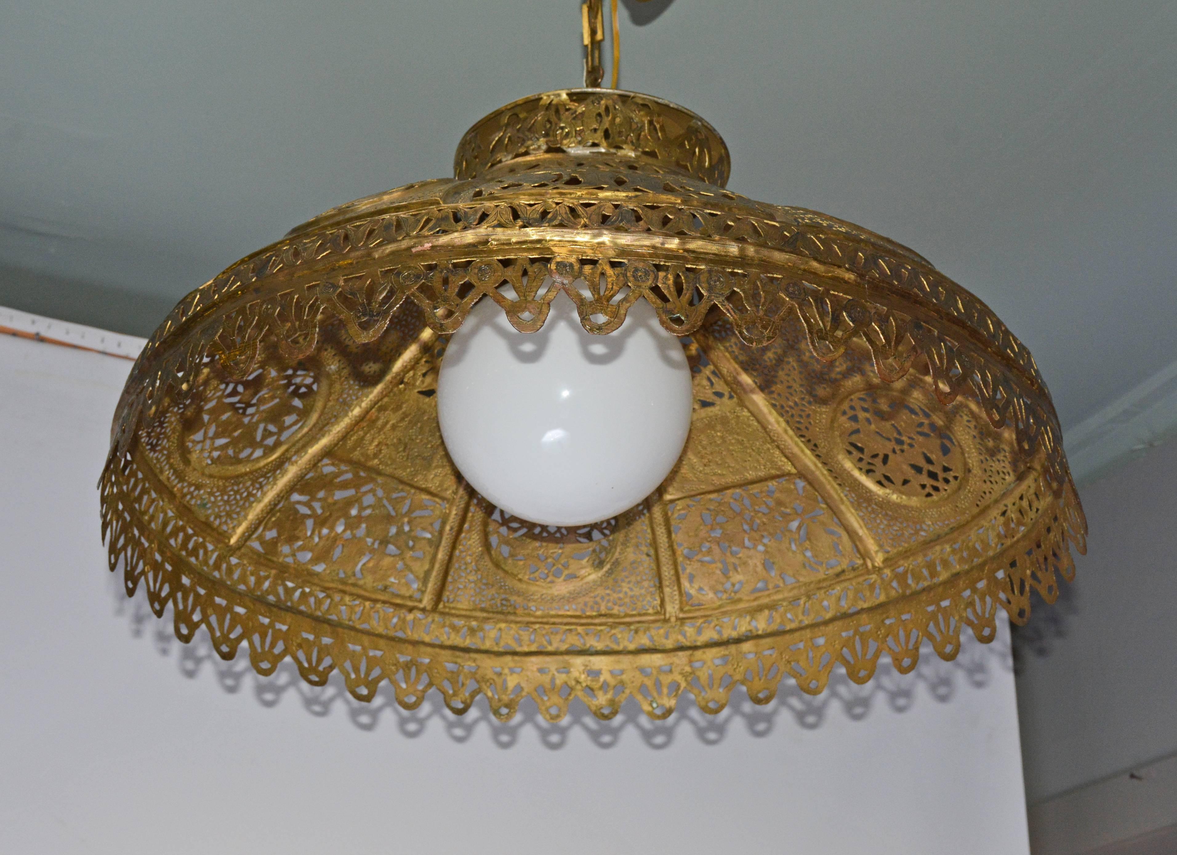 The Moorish Mideastern hanging lantern or chandelier is made of pierced brass decorated with leaves, fretwork and Arabic lettering and has been electrified for US use, socket and wiring for a single bulb. The 39