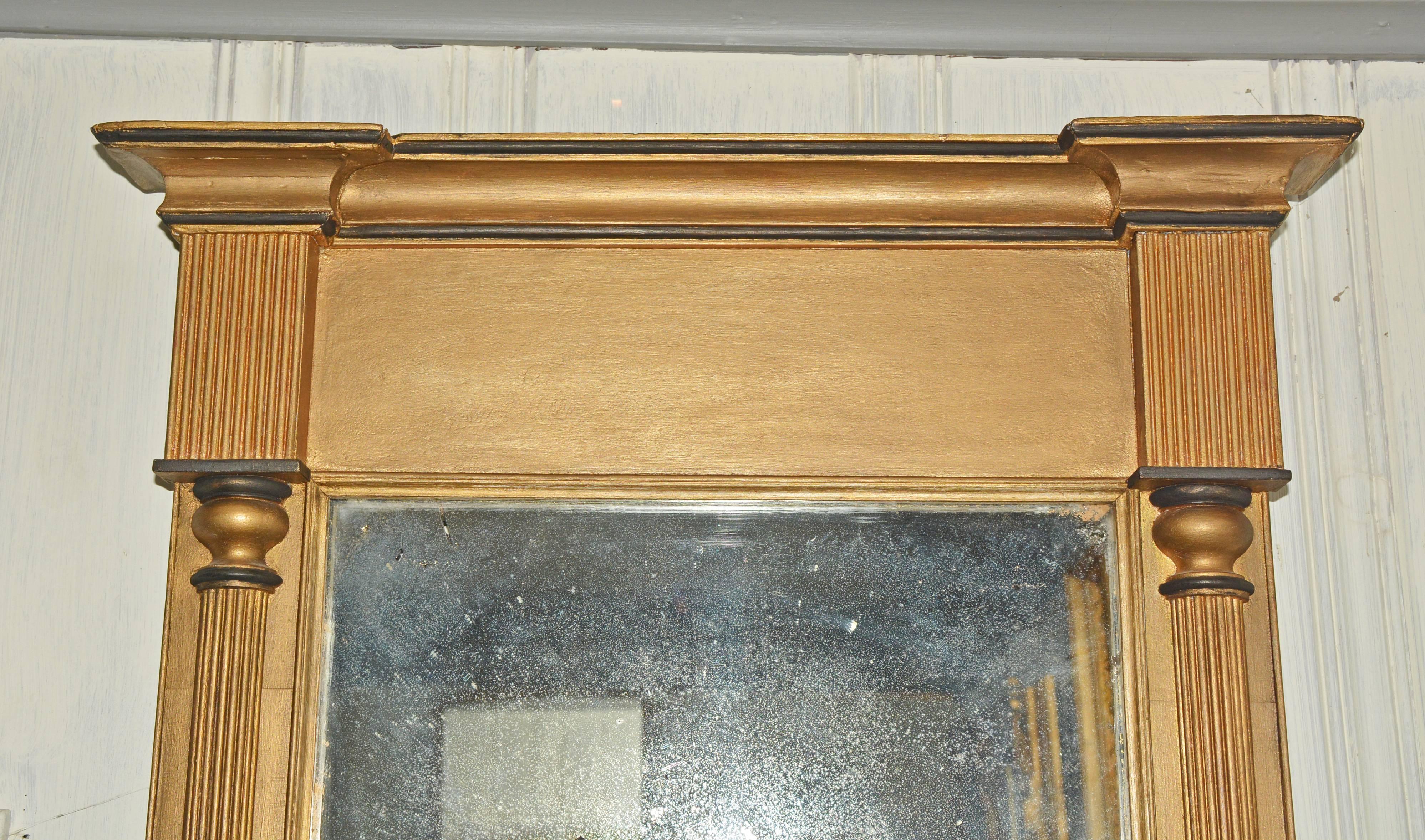 The Federal-style gilded pier mirror features side embellishments of tapered rope-style pilasters topped by fluted pilasters and an overhanging cornice. The mirror is wired for hanging.
 