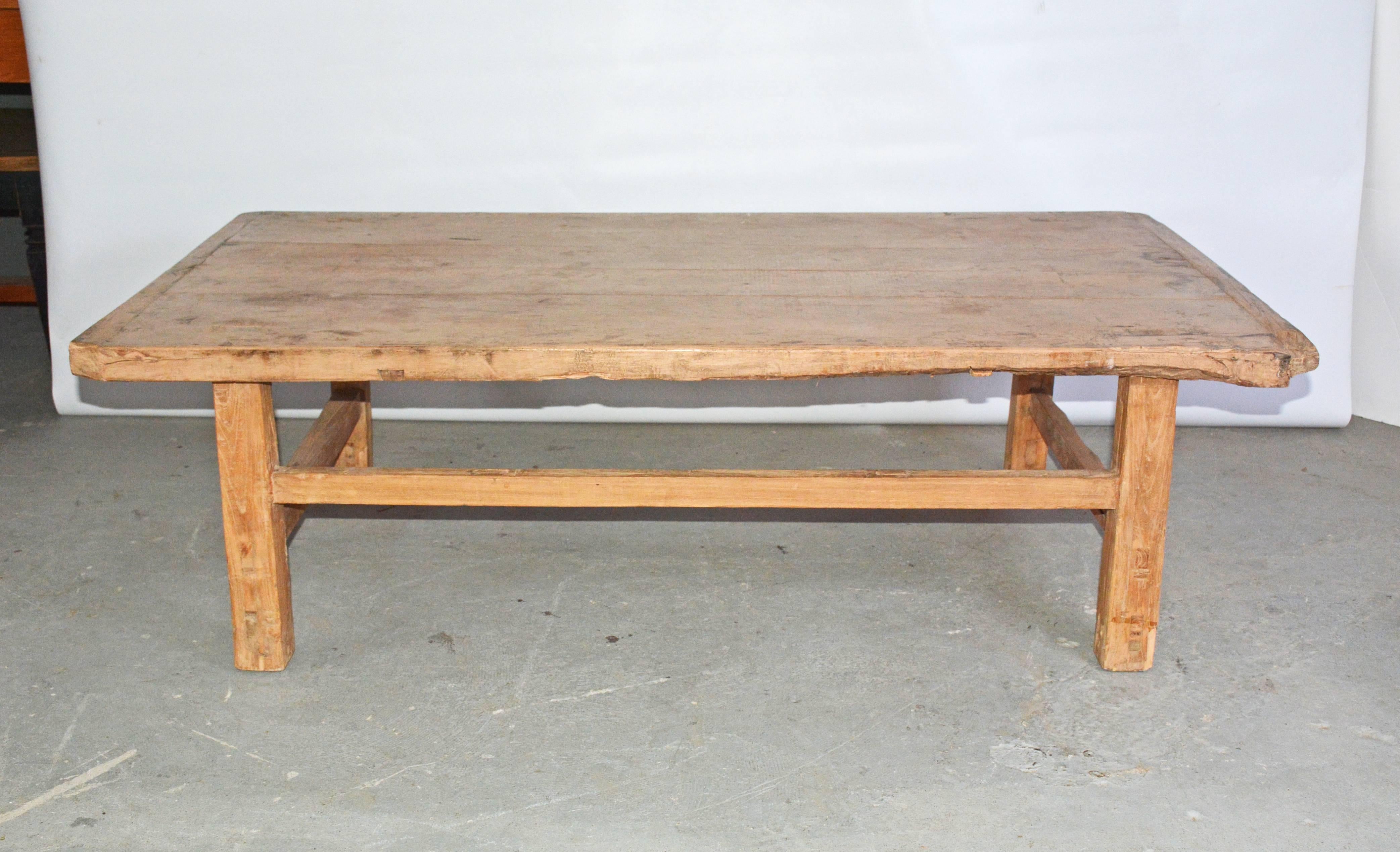The rustic plank top coffee table has legs secured by stretchers placed at two heights. Top has a wonderful aged patina with breadboard ends.