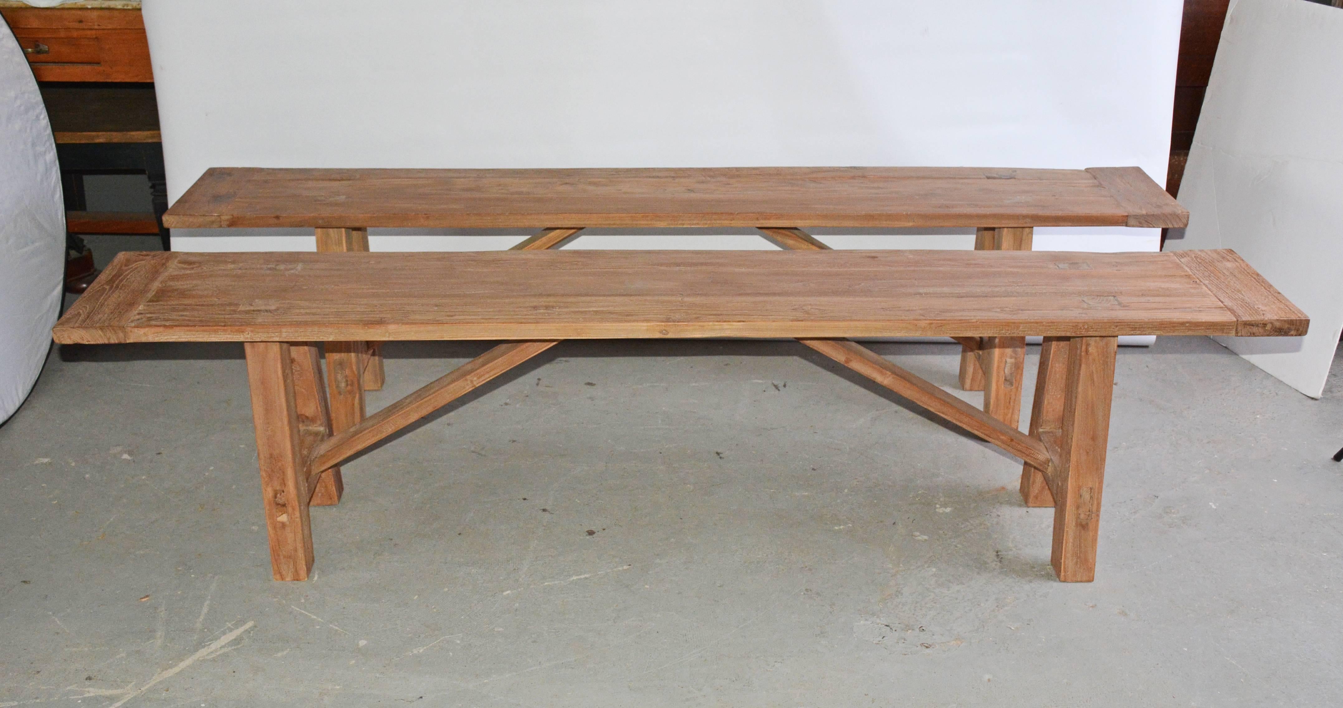 The pair of rustic indoor or outdoor teak benches has splayed legs, stretchers pegged into a breadboard top, stretchers and angled supports. Great for porch or garden dining seating. Newly made with reclaimed teak. Can be purchased individually.