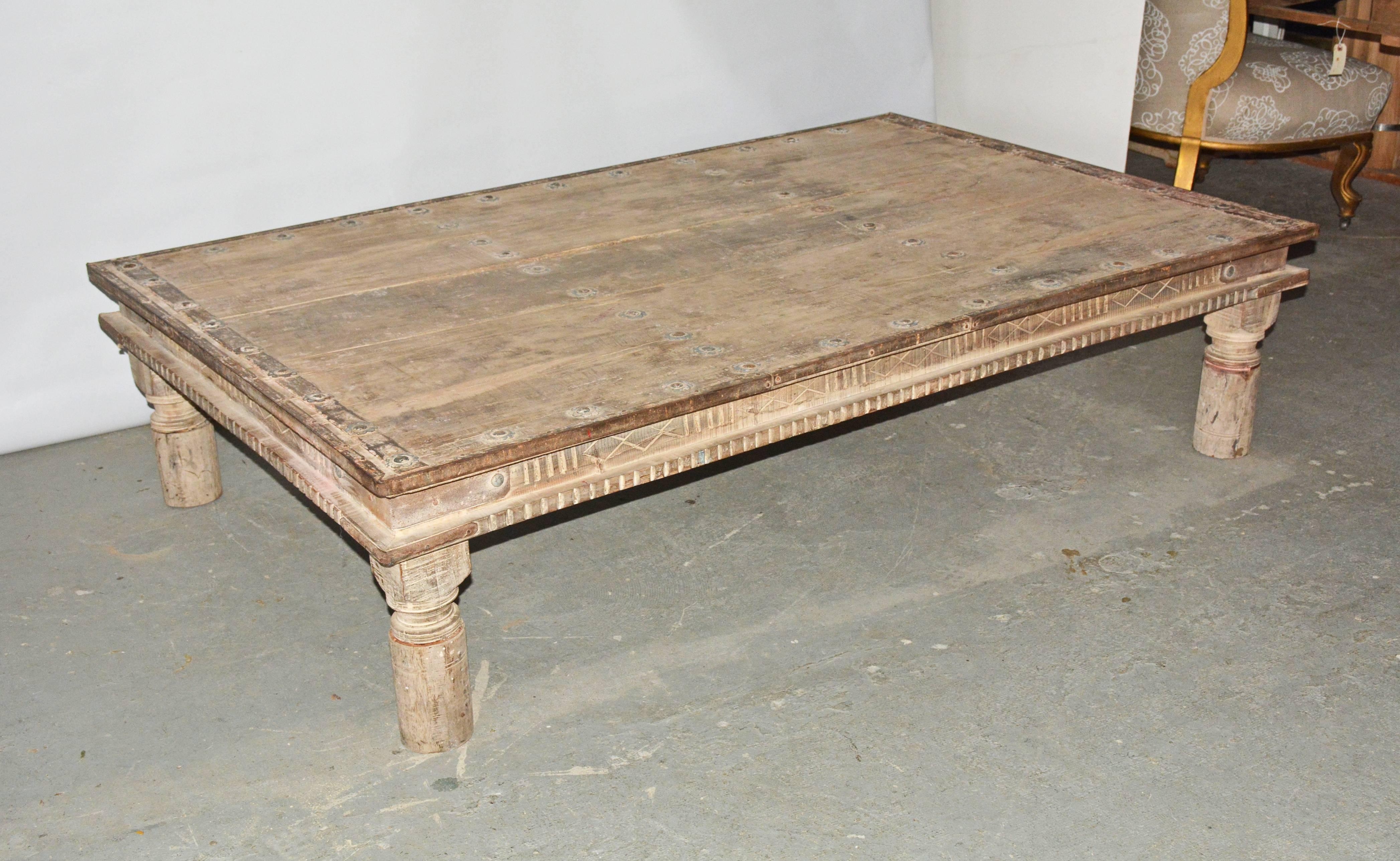 Impressive hand-carved coffee table made with hardwood planks with large iron decorations. Four shaped legs support this large rustic table. Table is in good antique condition with wear adding to its charm.