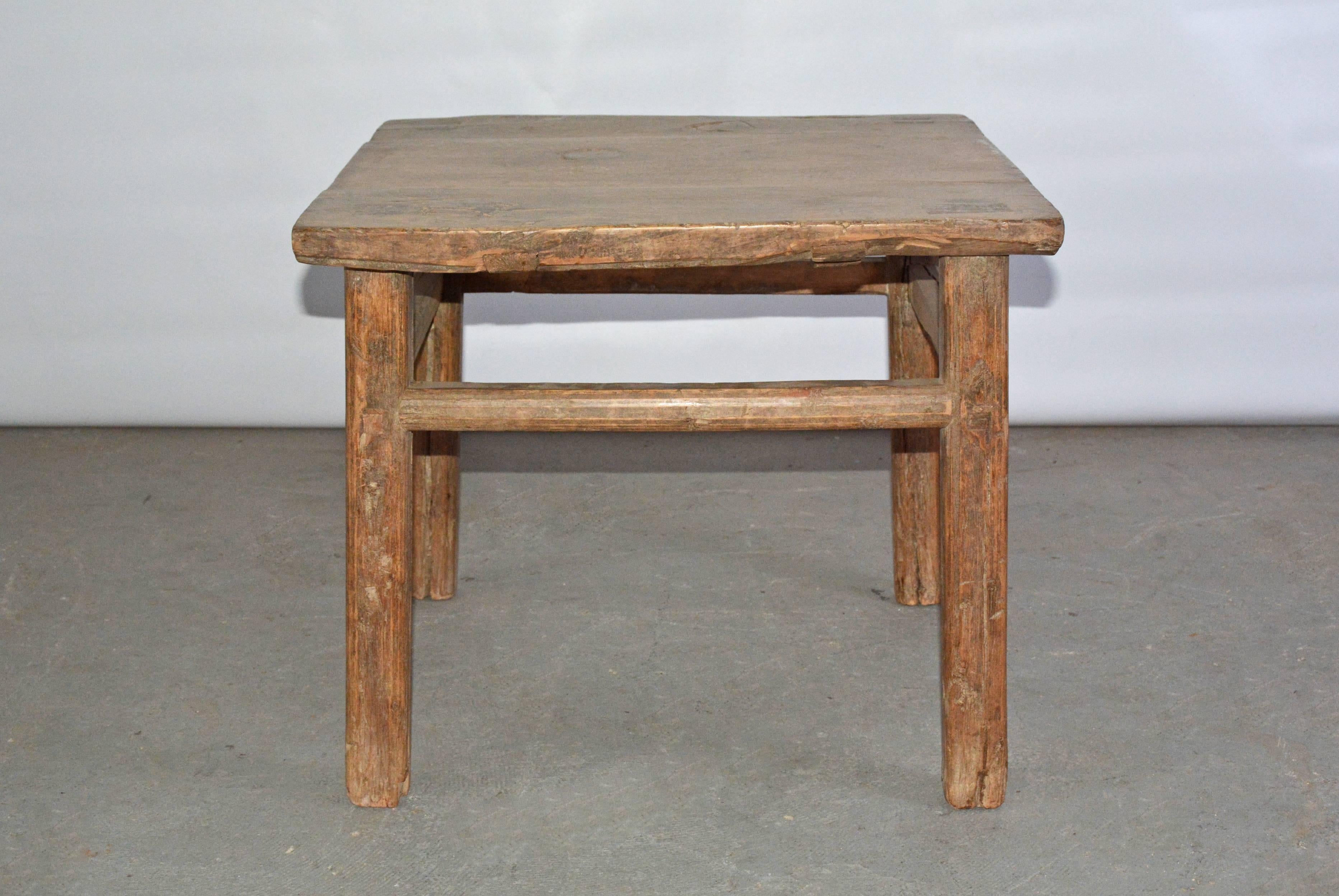 The rustic Asian-style teak wood side or coffee table has legs pegged into the top and stretchers pegged into grooves notched into the legs.