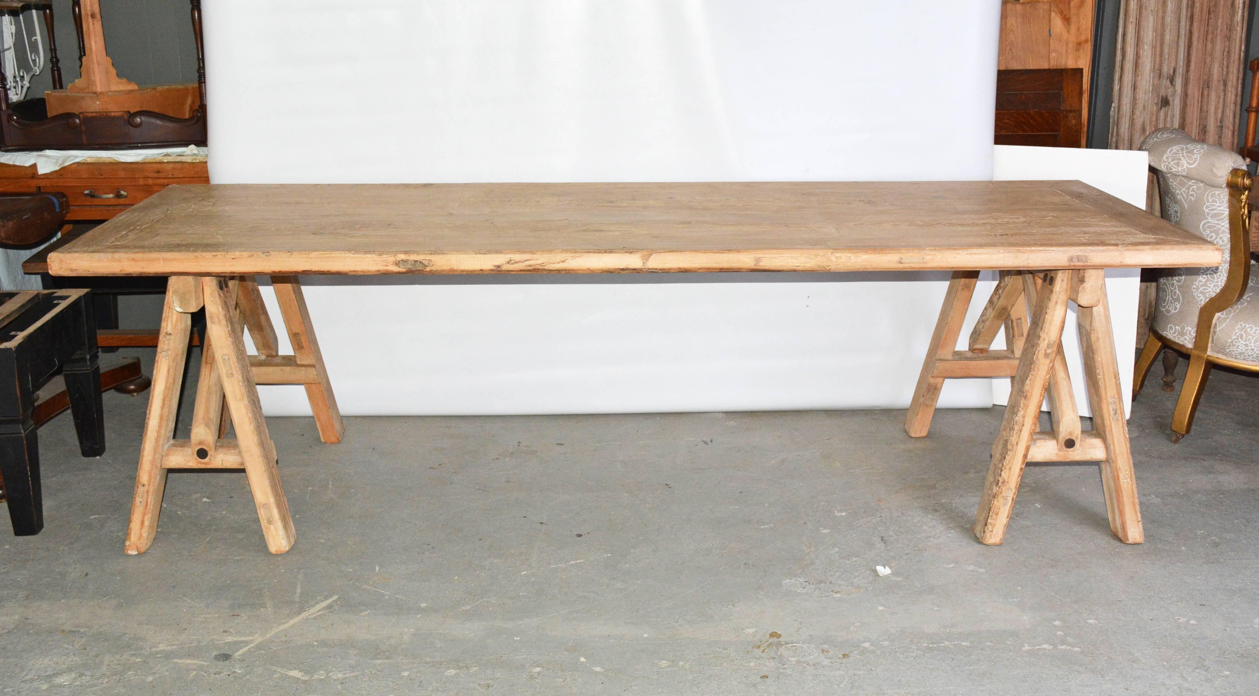 The rustic sawhorse dining table seats up to ten with framed planks. The sawhorse legs are secured with stretchers and angled supports. Newly made from reclaimed wood.