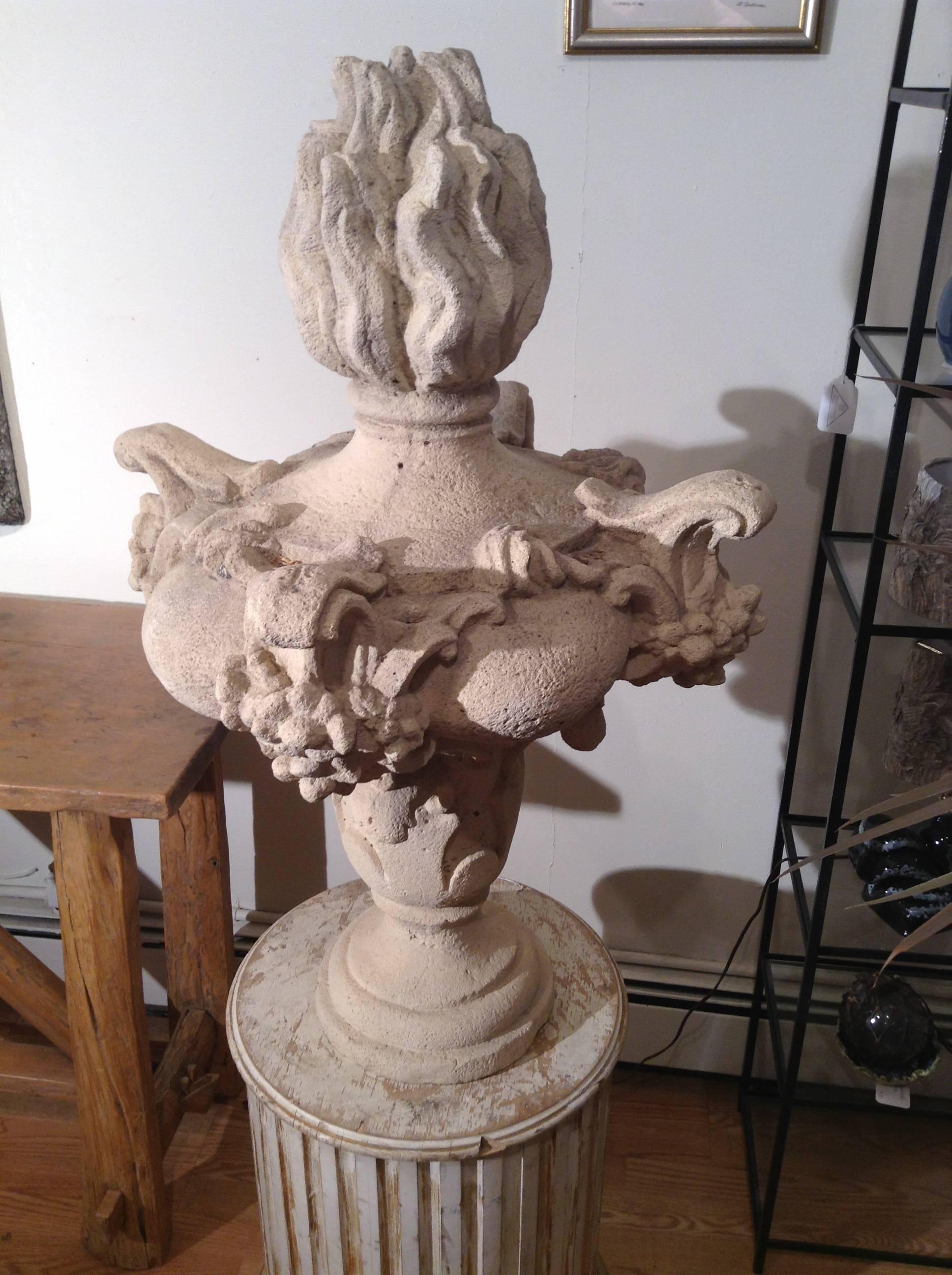 Made of composite limestone, the pair of antique flame urns are embellished with such classical motifs as flowers, scrolls and protruding cartouches. They are made to be seen from below. Urn and plinth can be sold separately.
  