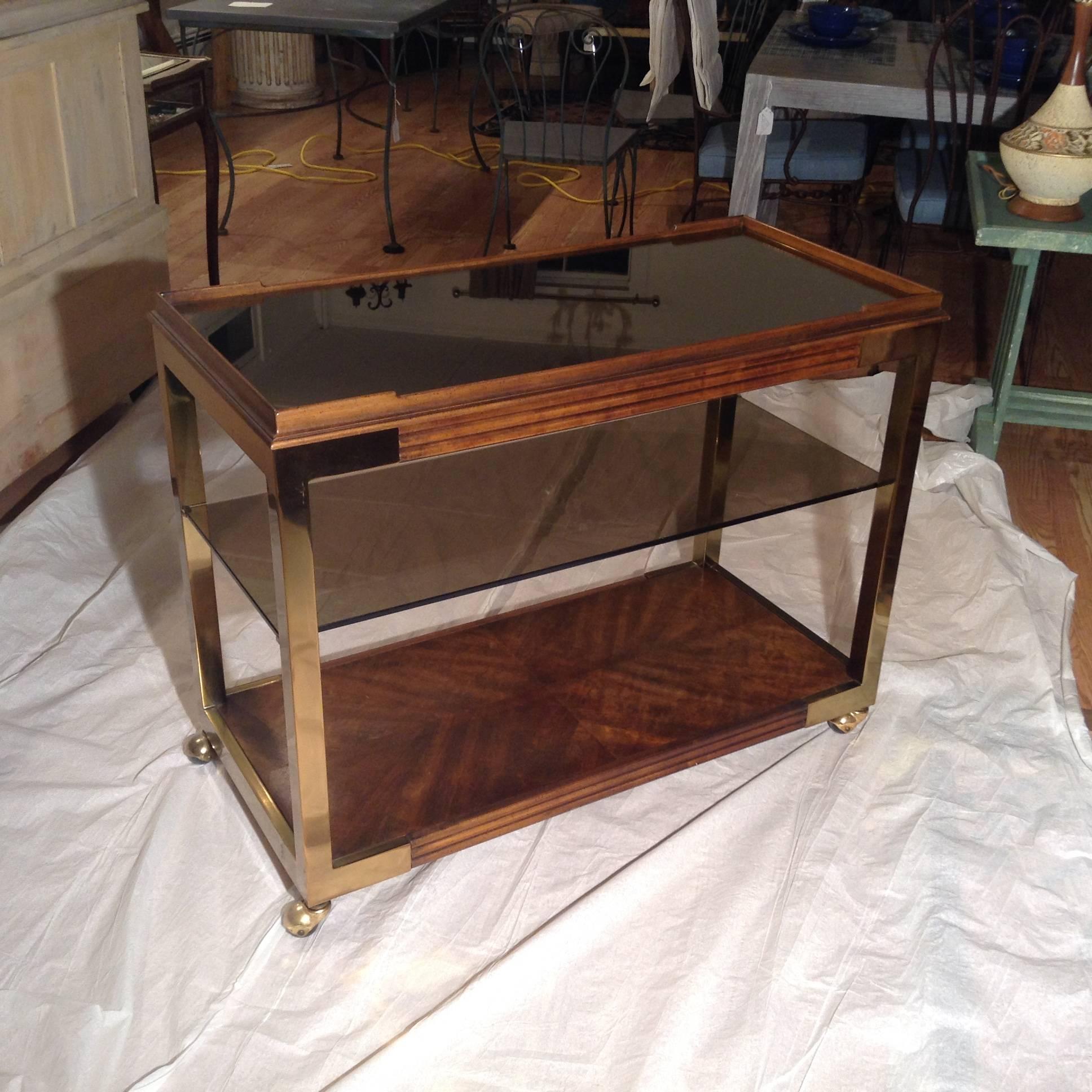 Drexel Heritage bar cart with caster wheels. Brass trim on wood. Smoke glass shelf and mirror top.
 