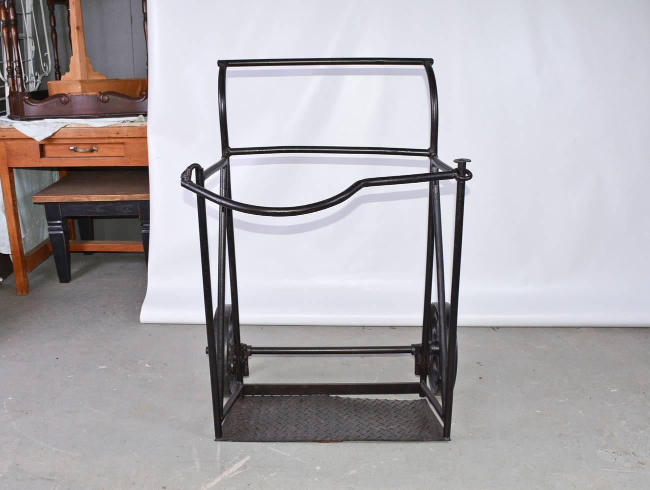 Vintage Industrial black iron two-wheeled cart or hand truck, circa 1900. Top front bar unhooks at left side and swivels.