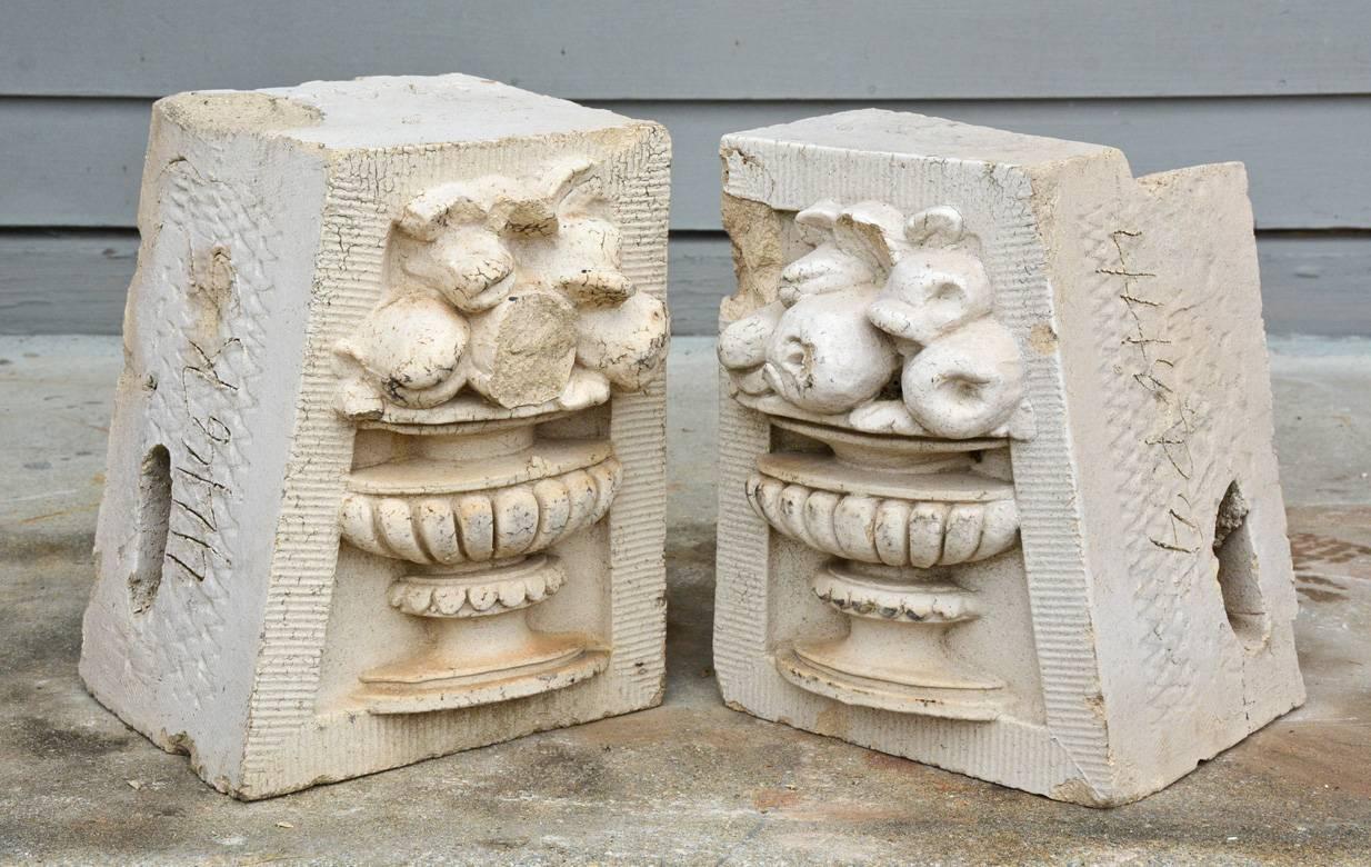 The pair of antique molded cement architectural decoration are embellished in high relief with urns filled with fruit. One side is slanted on each and both have deep backs that are hollow. Great as garden decorative object.