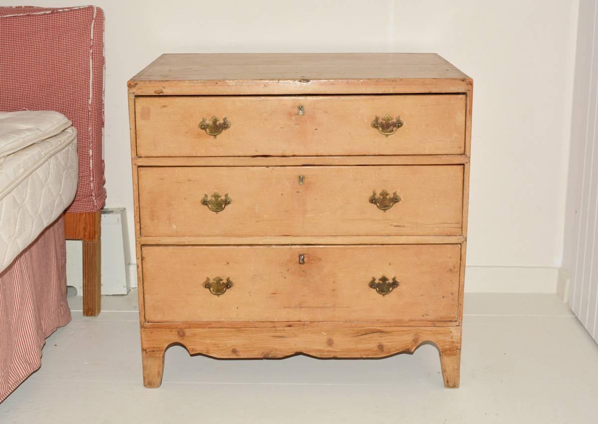 The rustic American country pine chest of drawers, nightstand or end table has three drawers, brass pulls, key holes and elongated scalloped aprons at the bottom on three sides.
Night stand, side table.